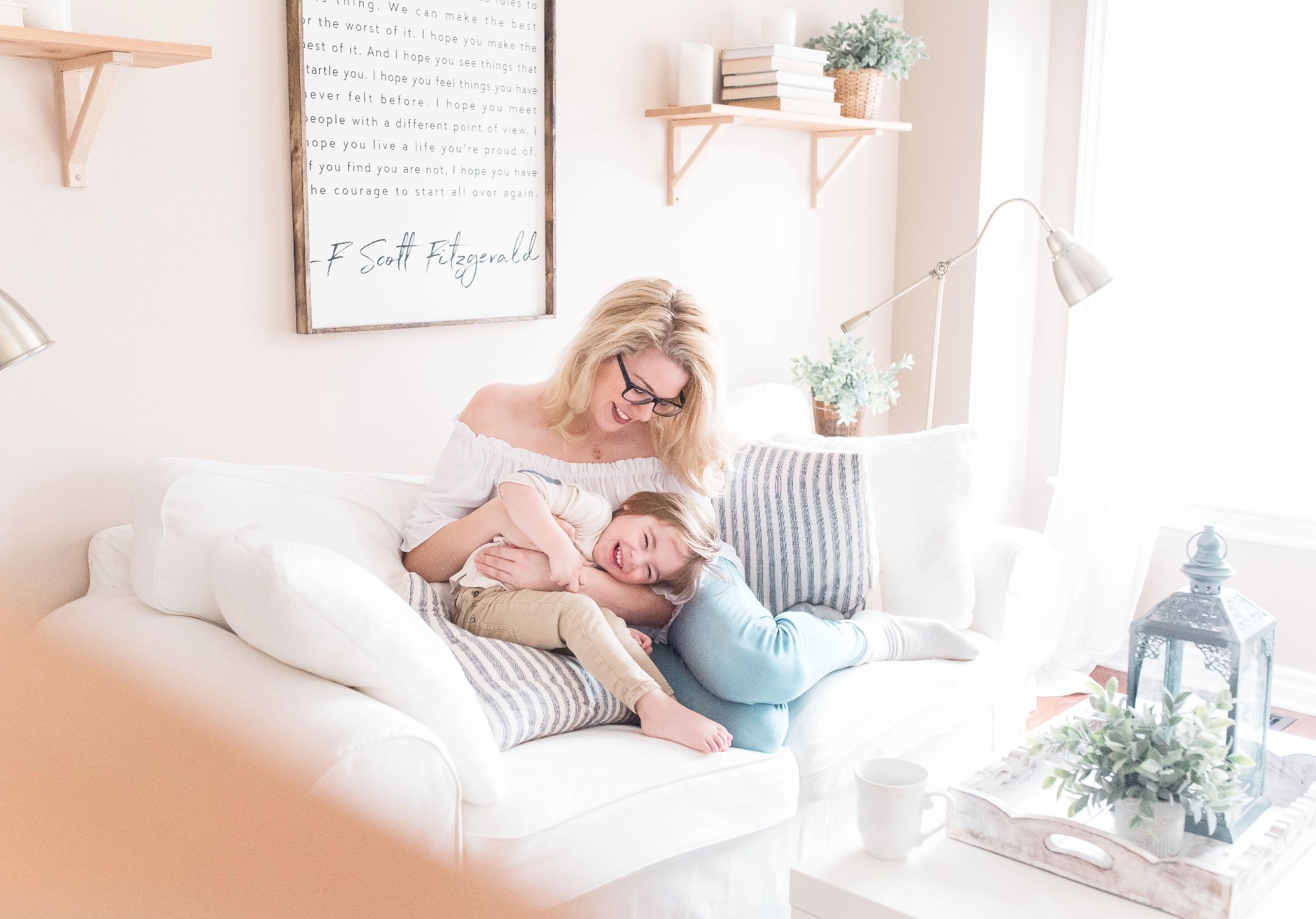 Mother smiling and cuddling son on a couch in a living room.