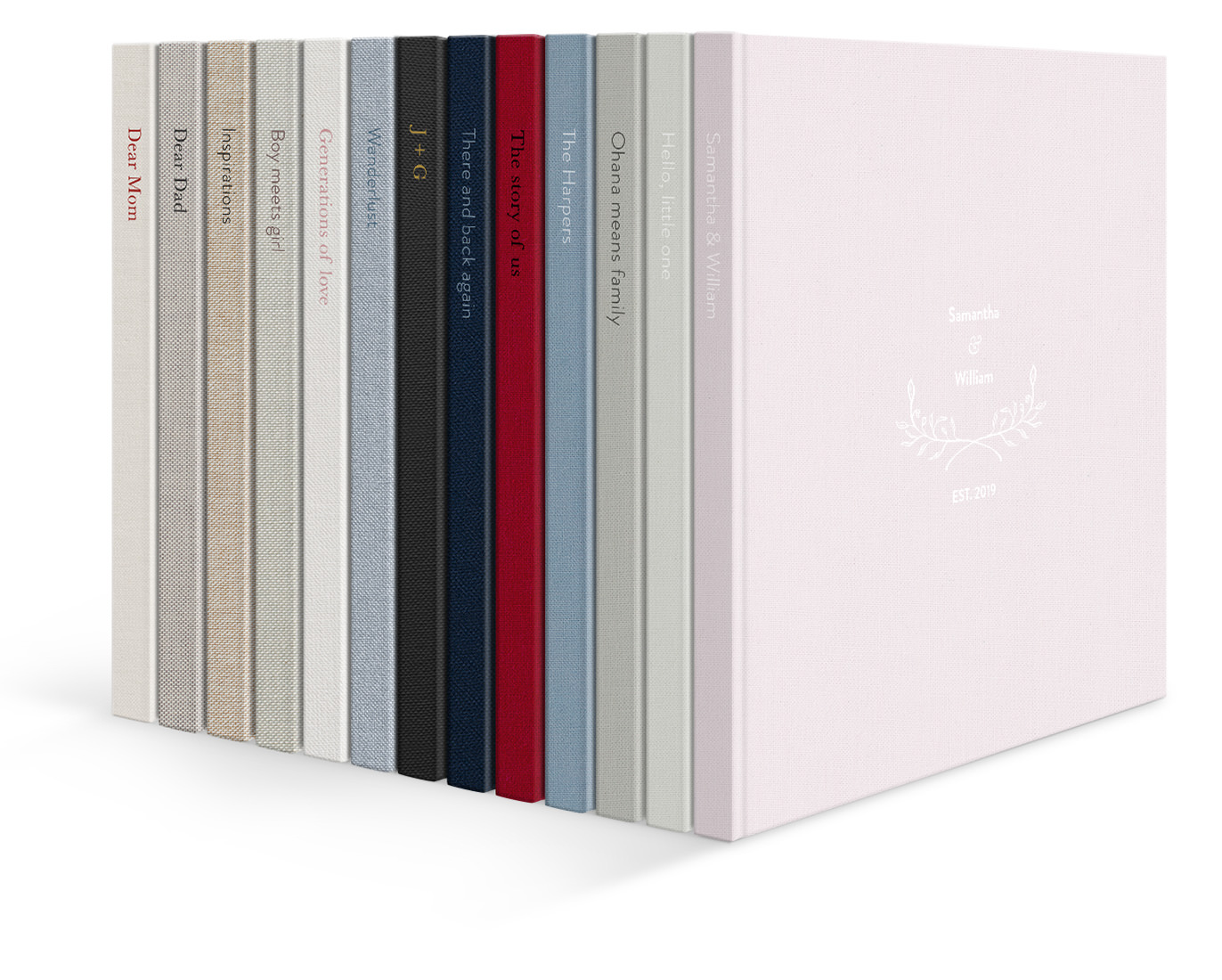 Stack of 13 photo books each with spine text and different fabric colors