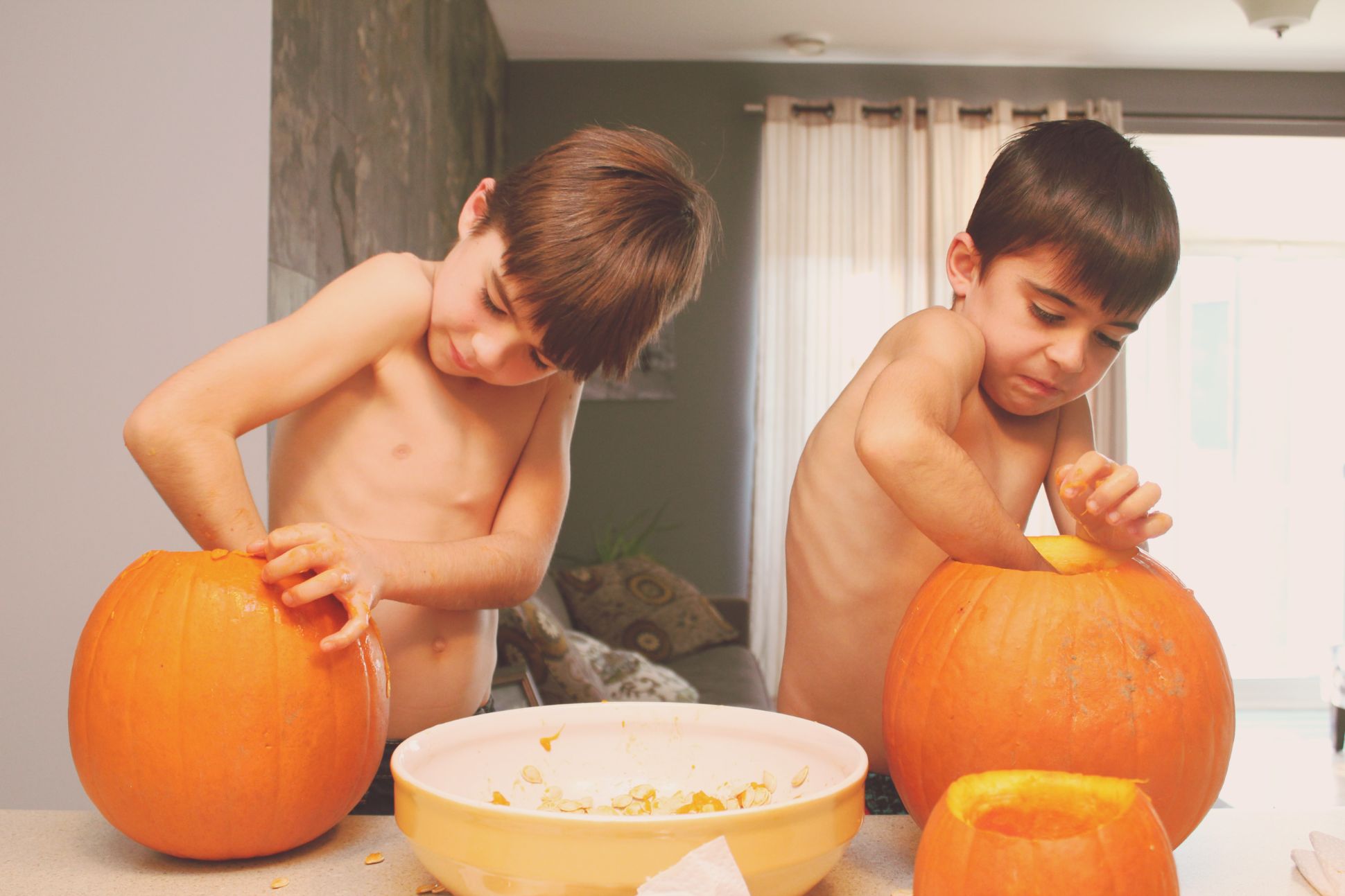 Two boys hollowing out pumpkins