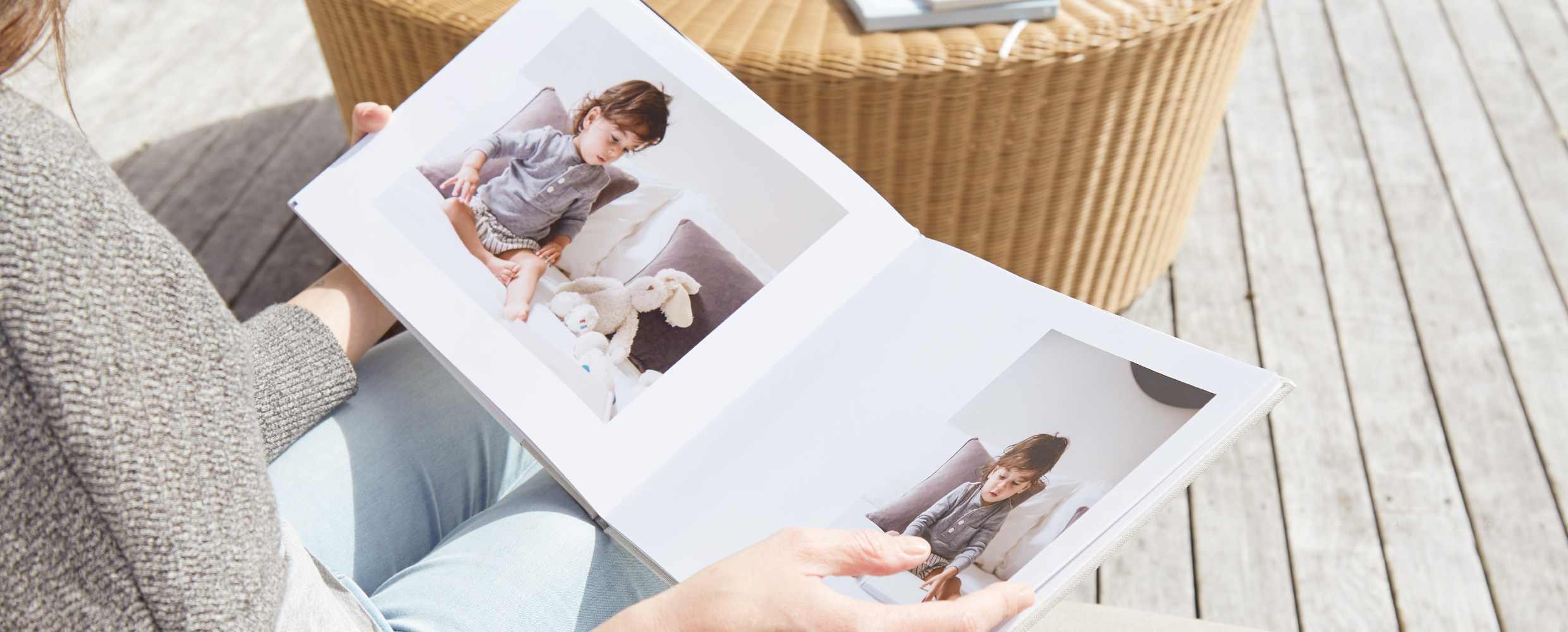 Woman outdoors flipping through open photo book with images of their child.