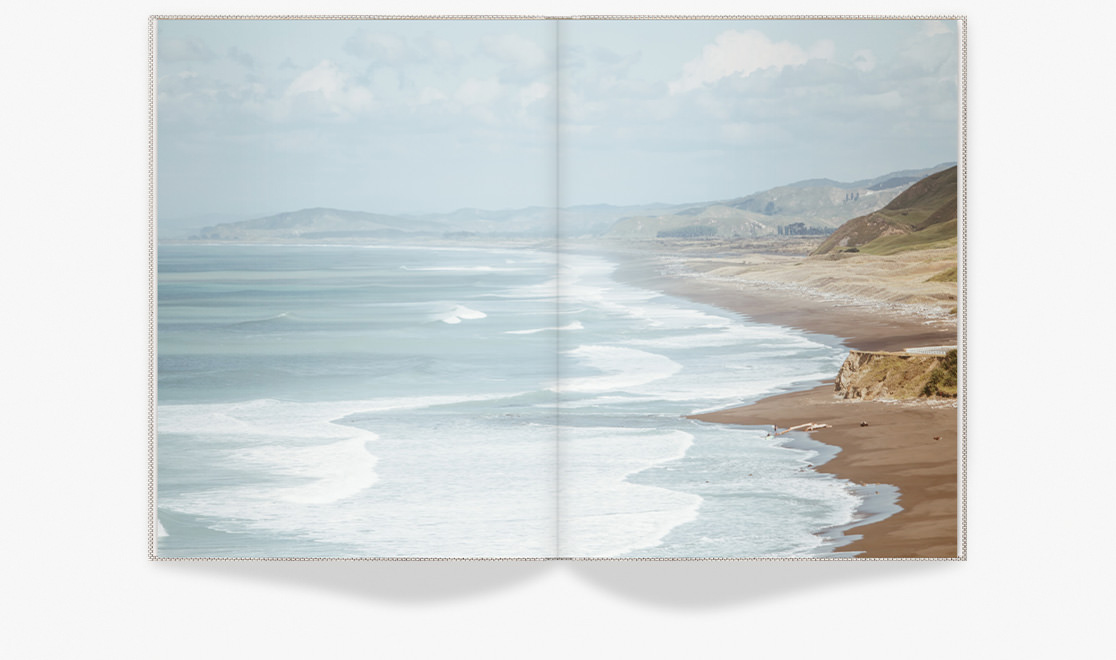 Open photo book with image of the sea and beach.