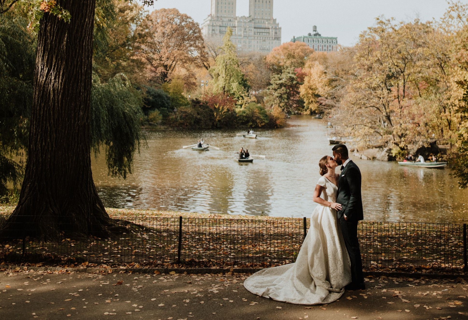 Bride and groom kiss in park by water