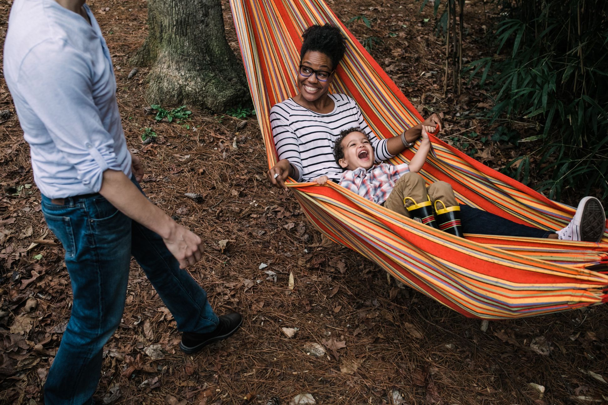 Mother and son smiling in a hammock outside.