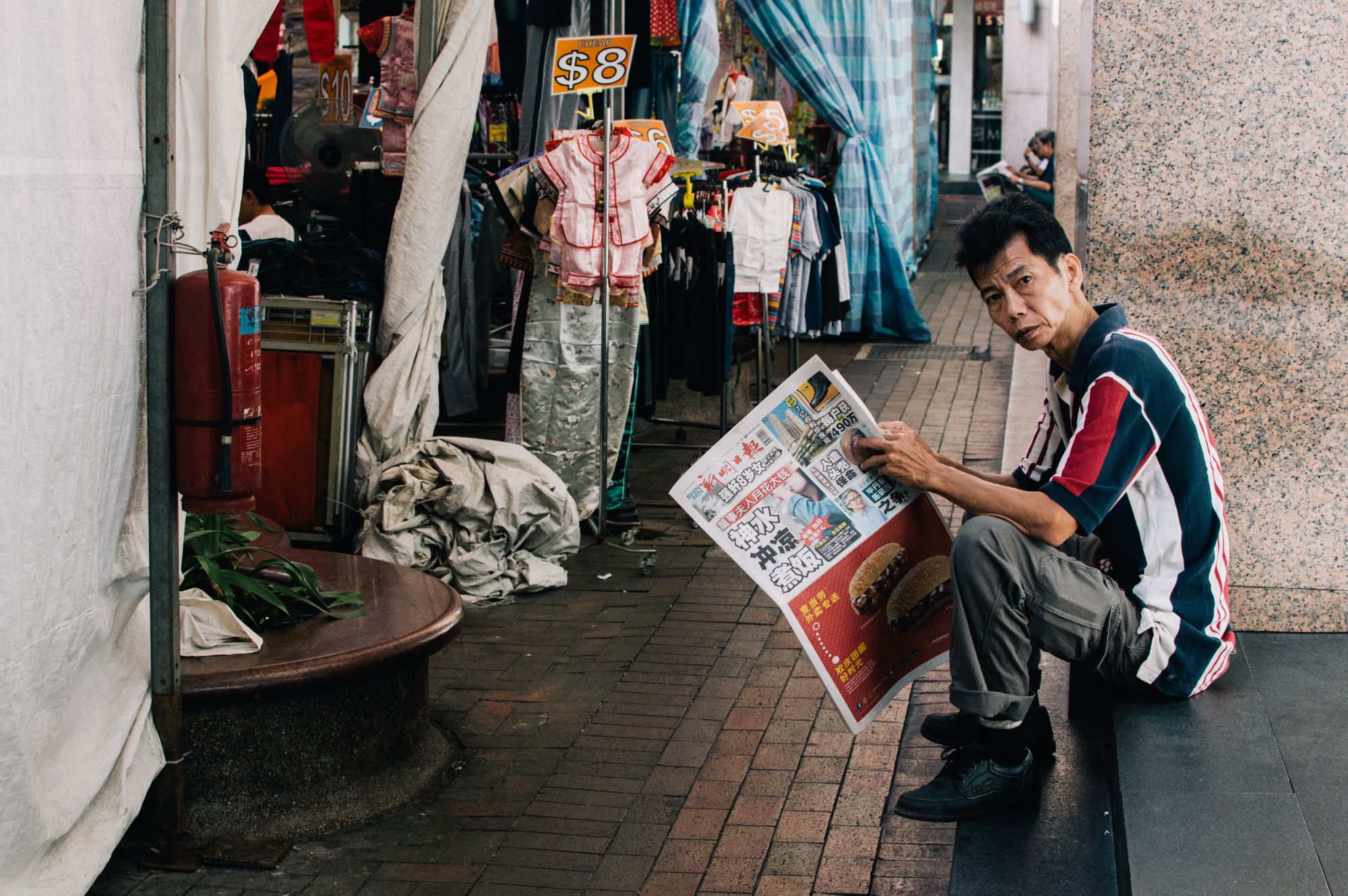 Man sitting and reading newspaper outside shop