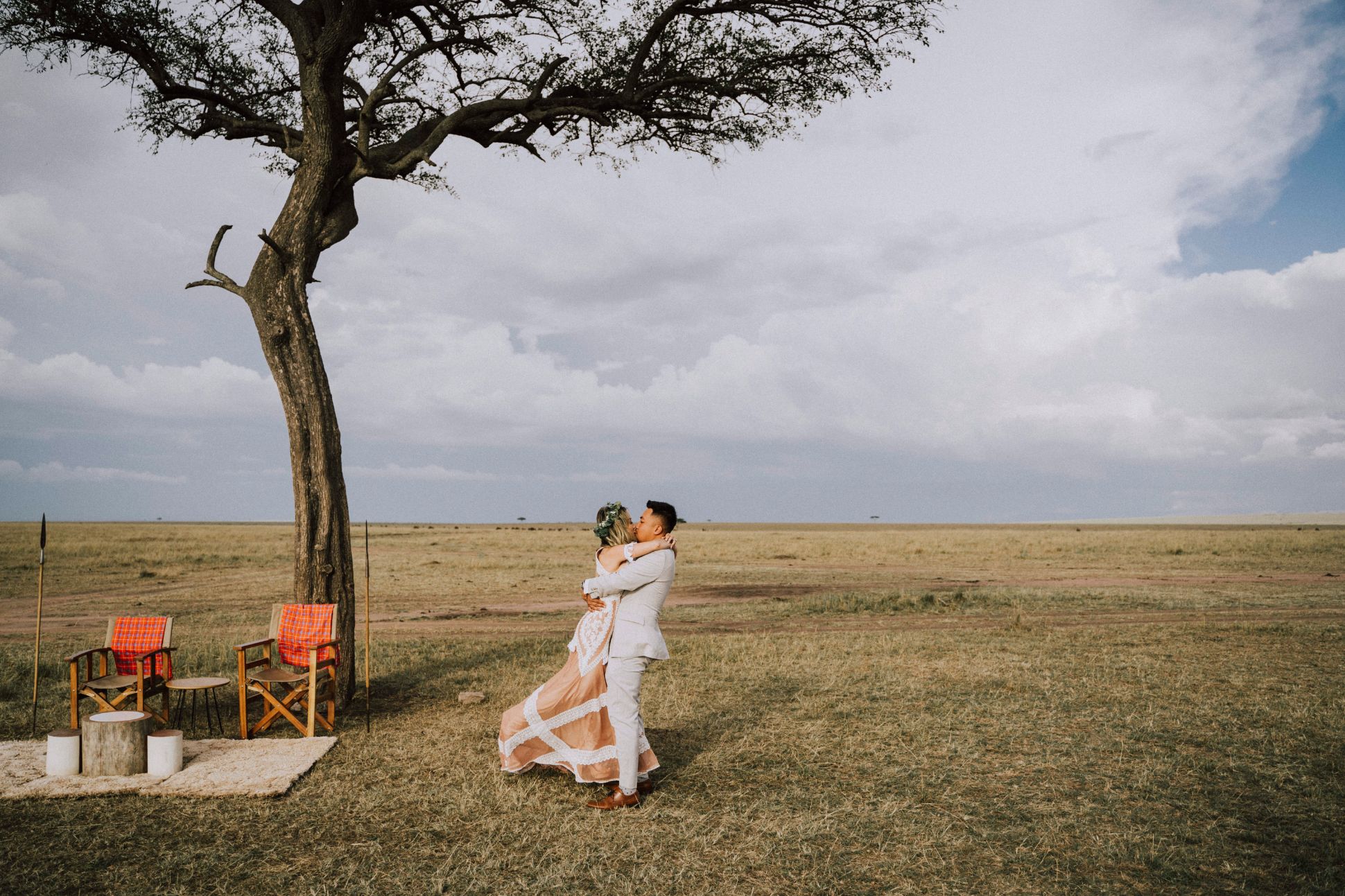 Bride and groom kiss in field