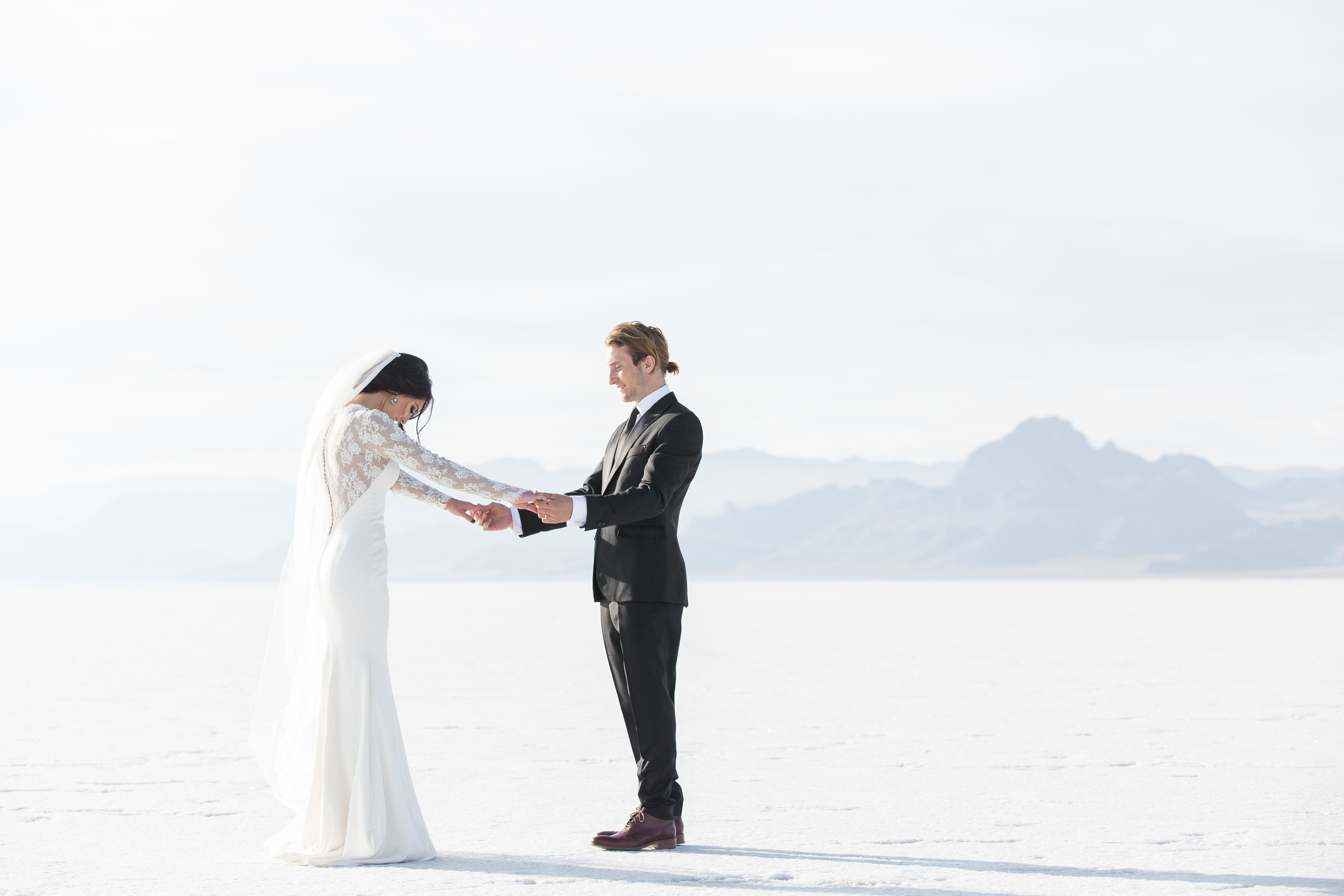 Newlyweds holding hands on salt flat