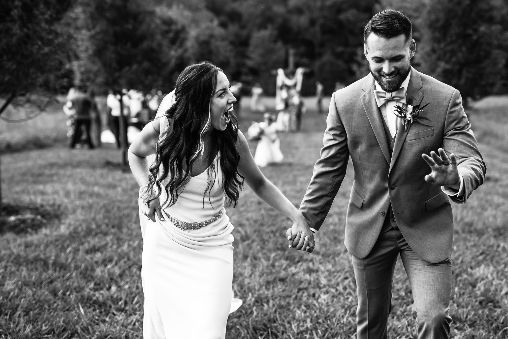 Newlywed couple walking hand in hand in field
