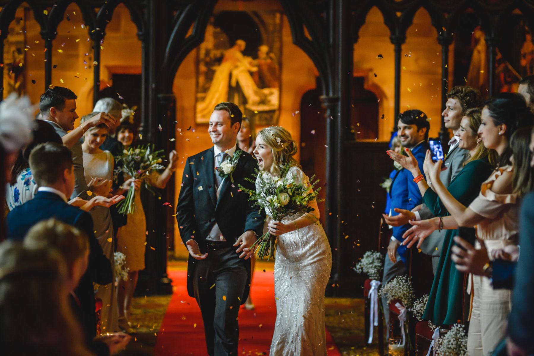 Bride and groom smiling as guests throw confetti