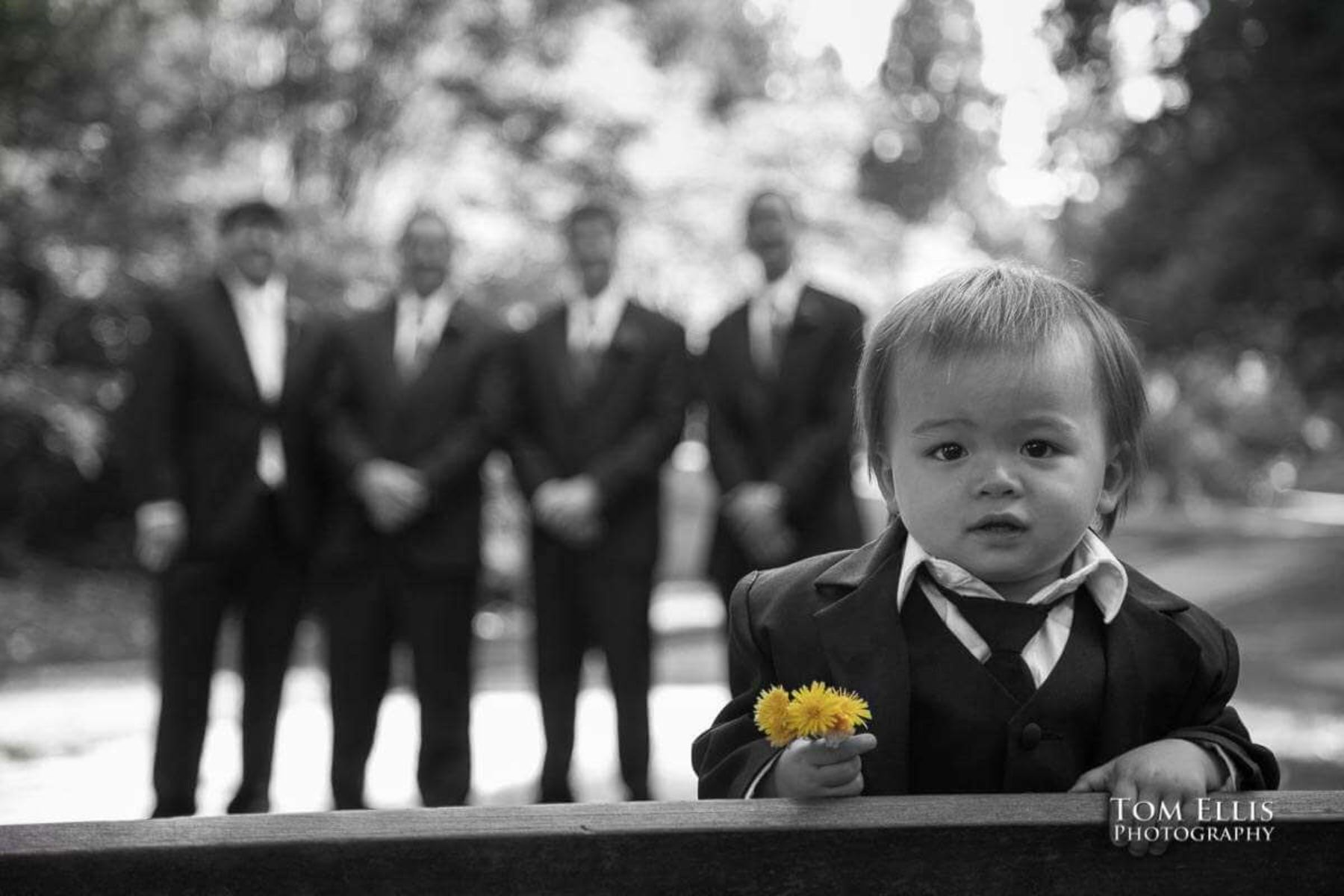 Young boy holding flowers with groomsmen in background