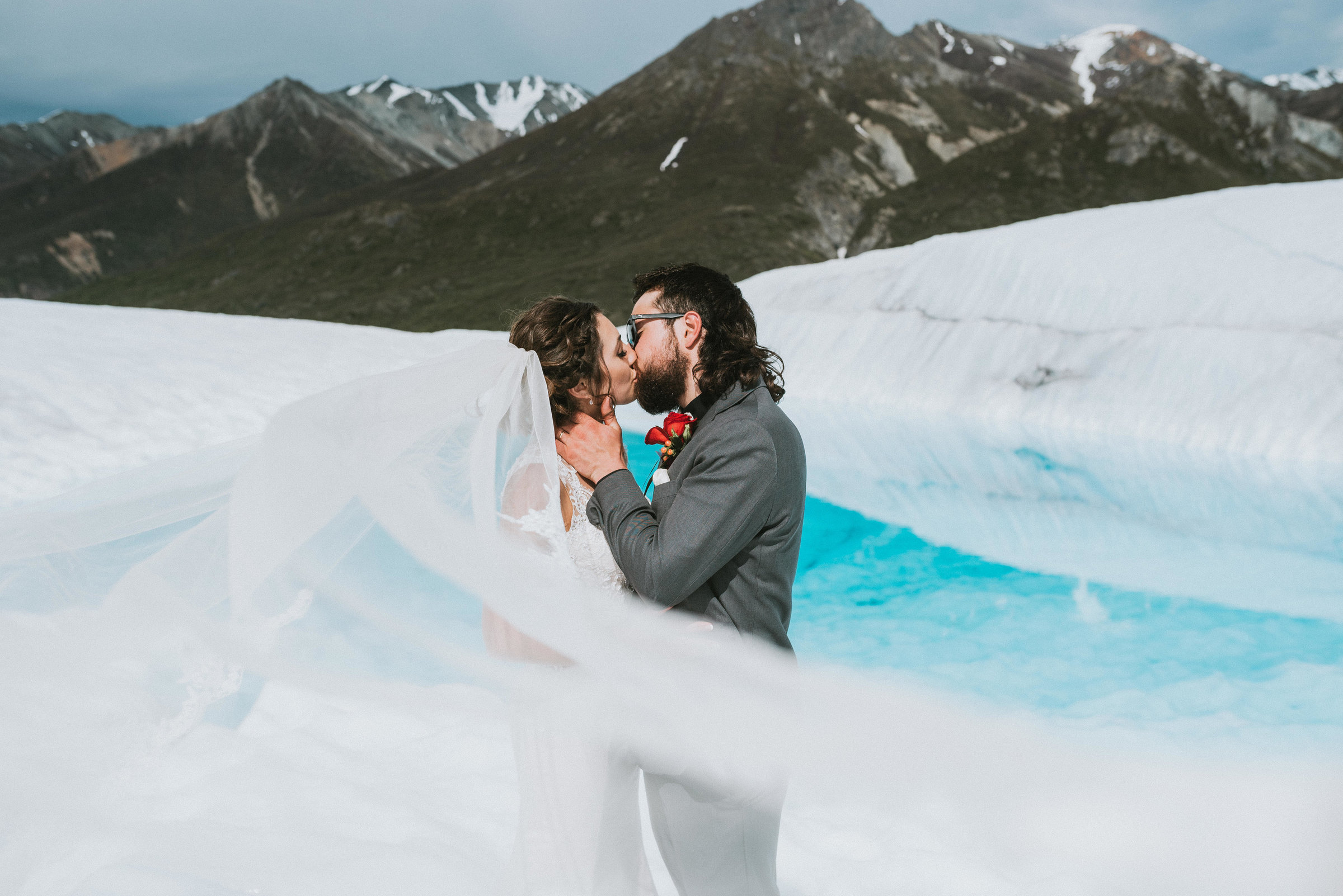 Newlyweds kissing in mountains