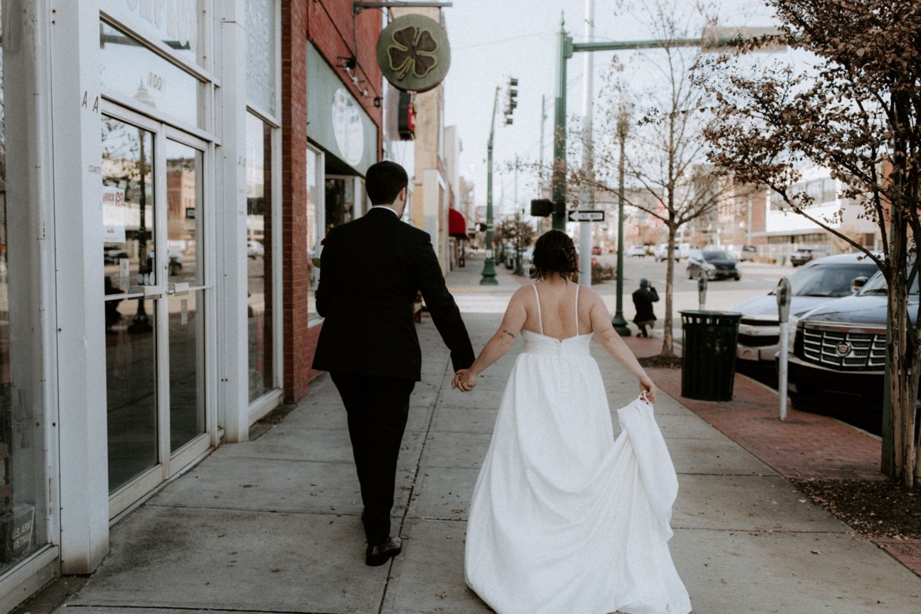 Bride and groom holding hands and walking down the street