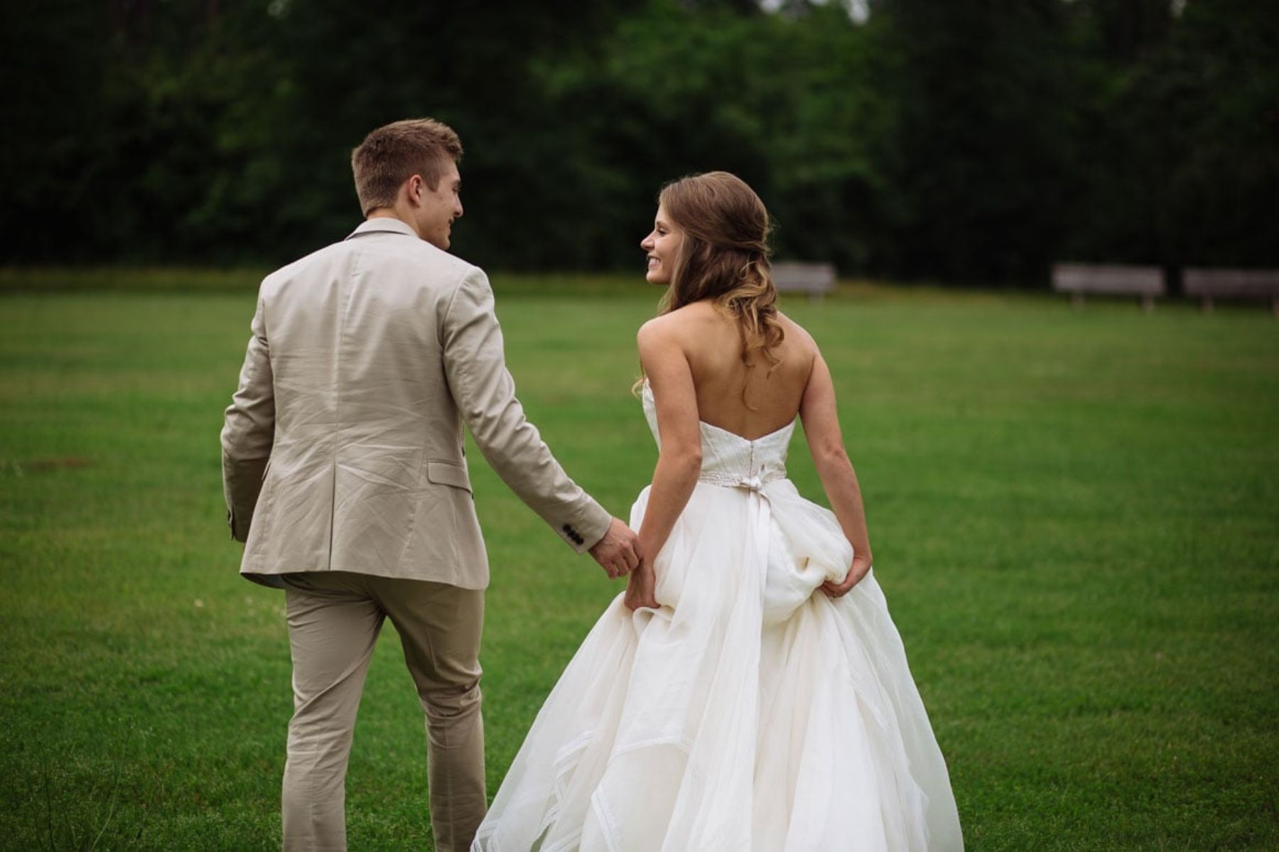 Bride and groom walk together in field