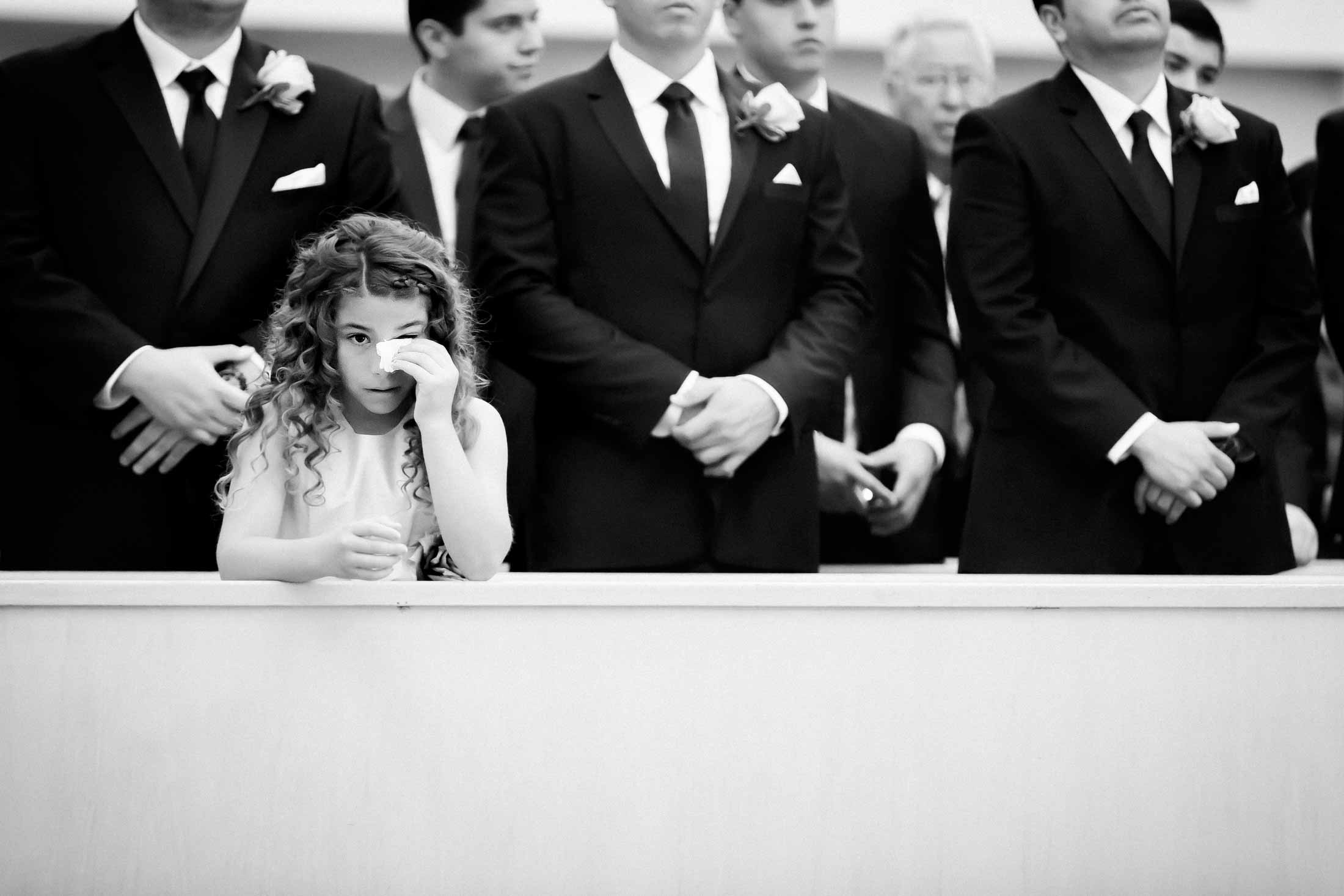 Young girl among wedding guests wiping tears