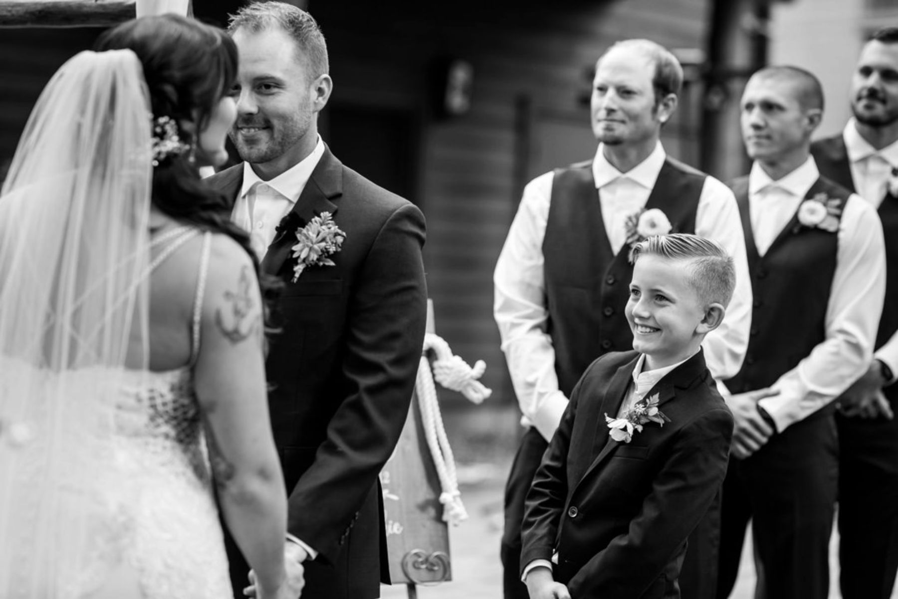 Young boy smiling at bride alongside groomsmen