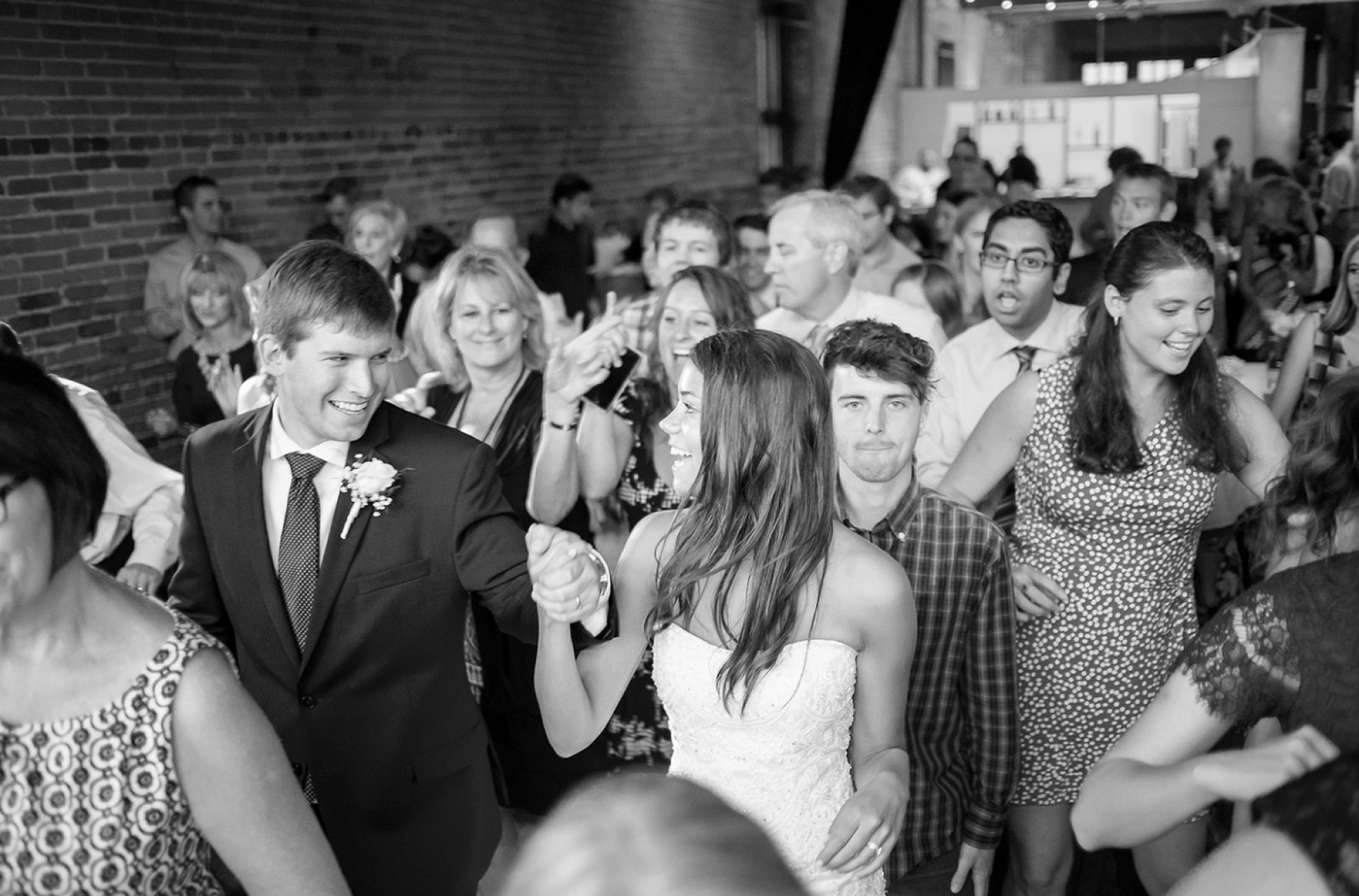 Bride and groom walking hand in hand in crowd