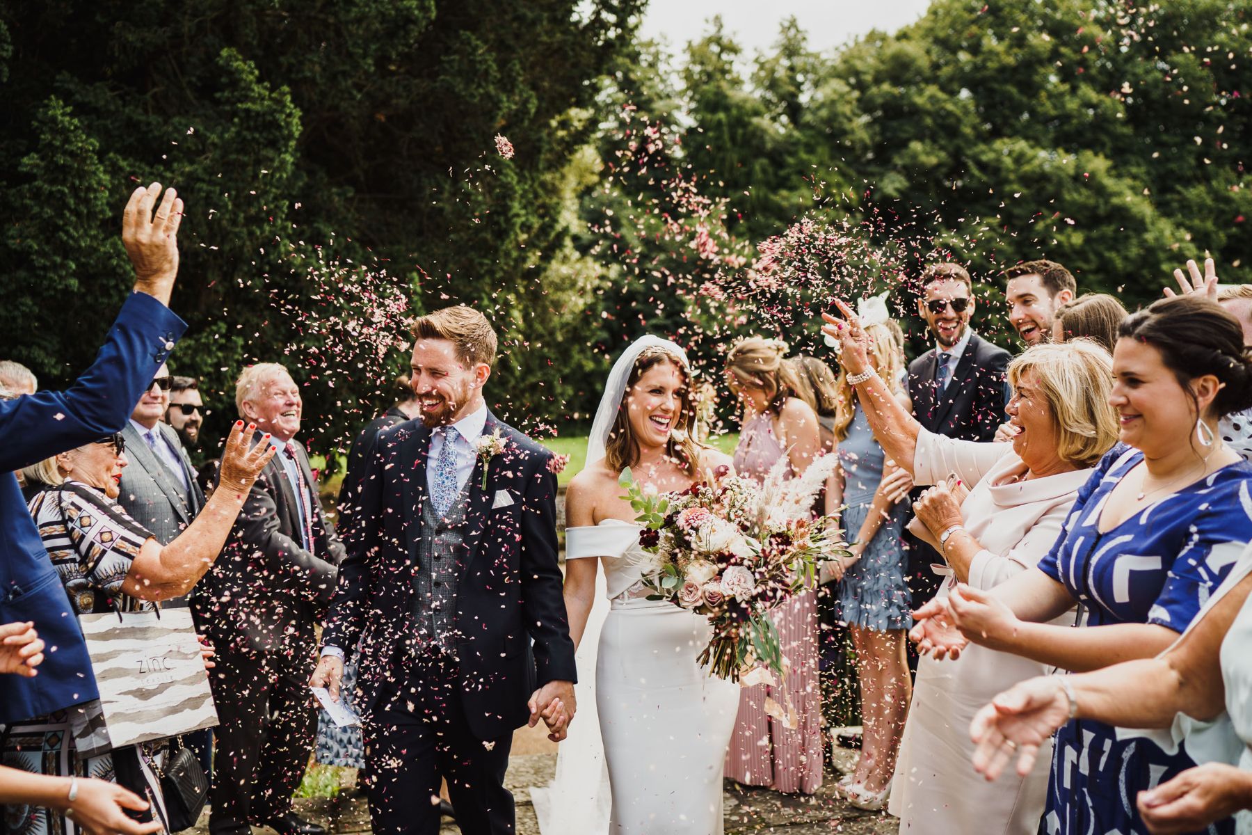 Wedding guests throwing confetti on smiling newlywed couple