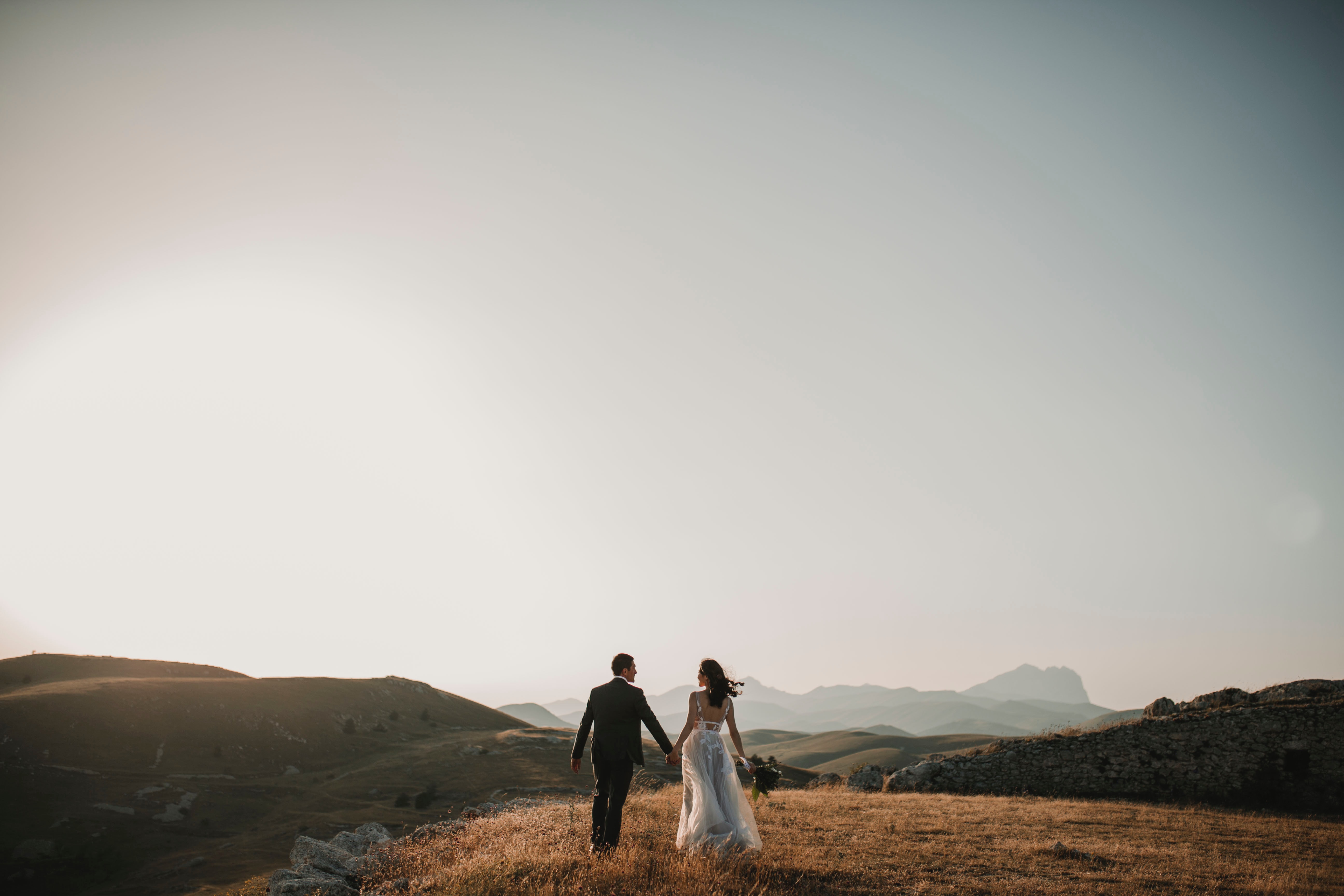 Newlyweds walking hand in hand in a field