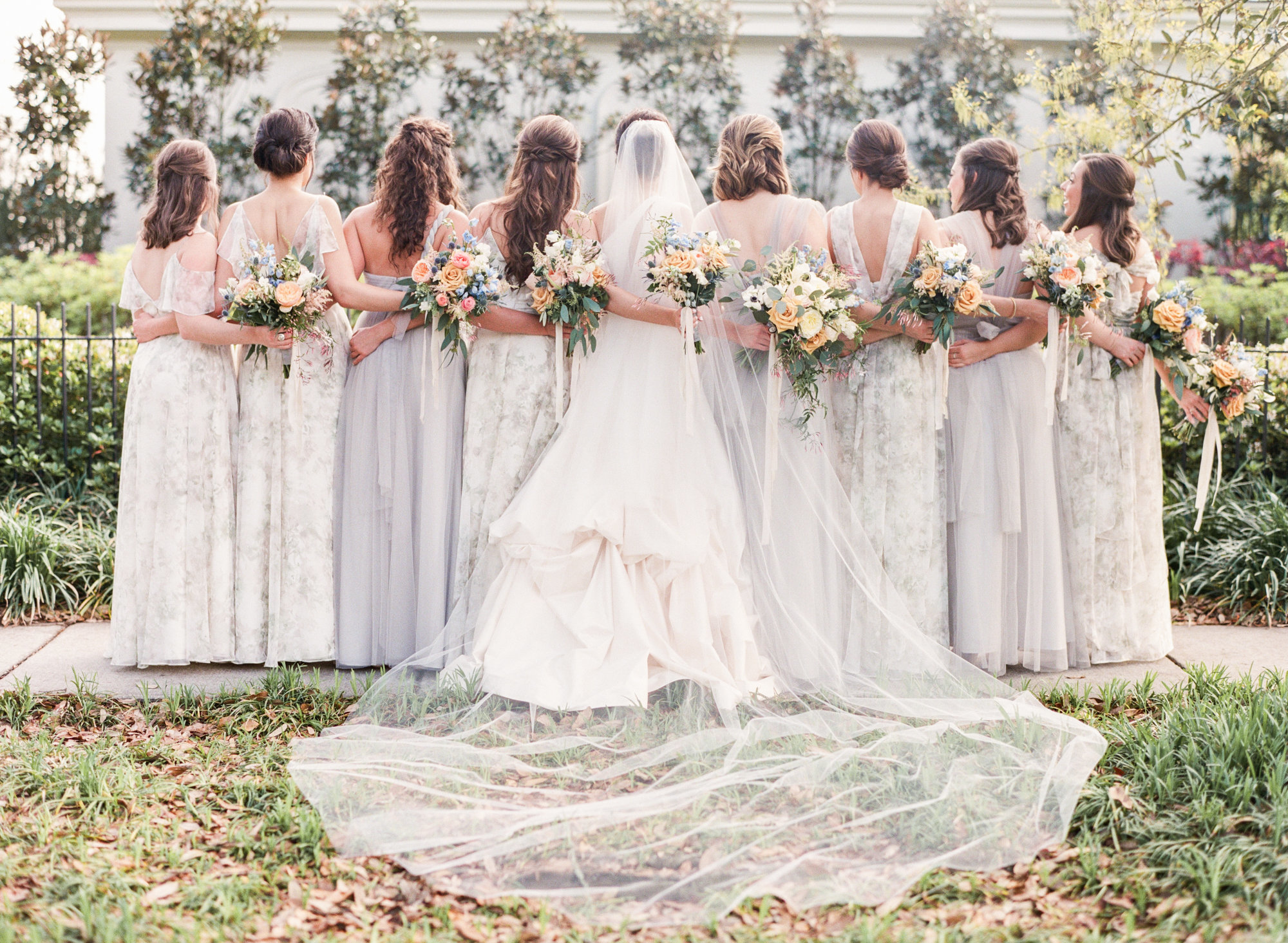 Bride and bridal party posing arm in arm