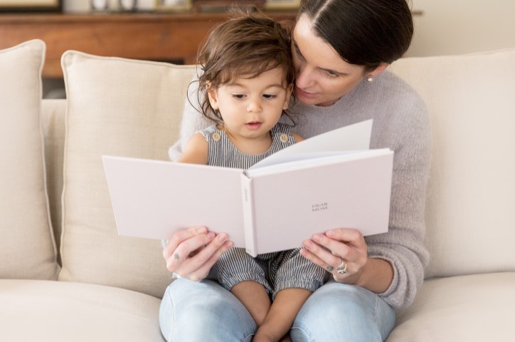 Mother and child looking at a photo book on the couch.