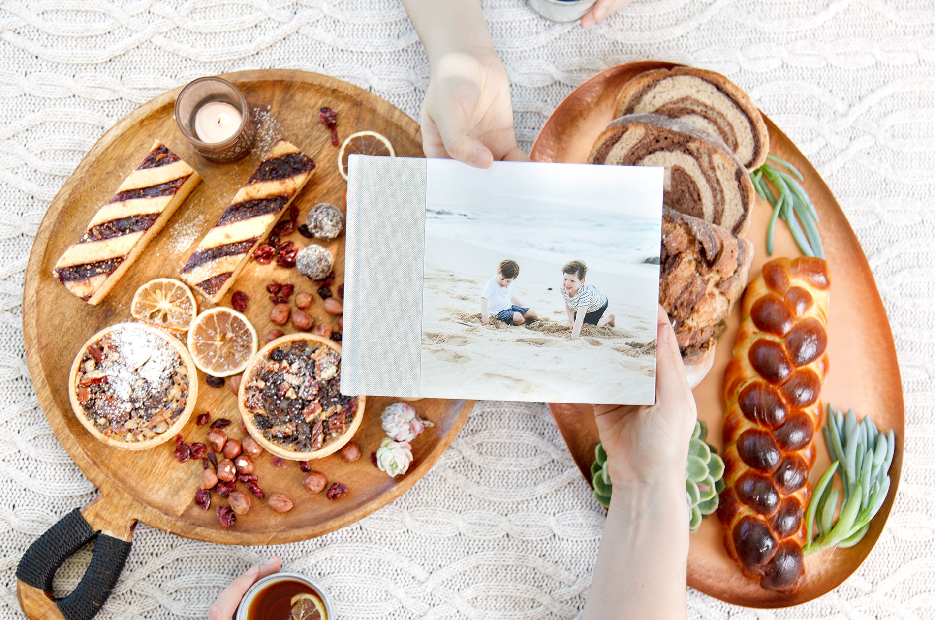 Landscape photo book being passed over a table of food platters.