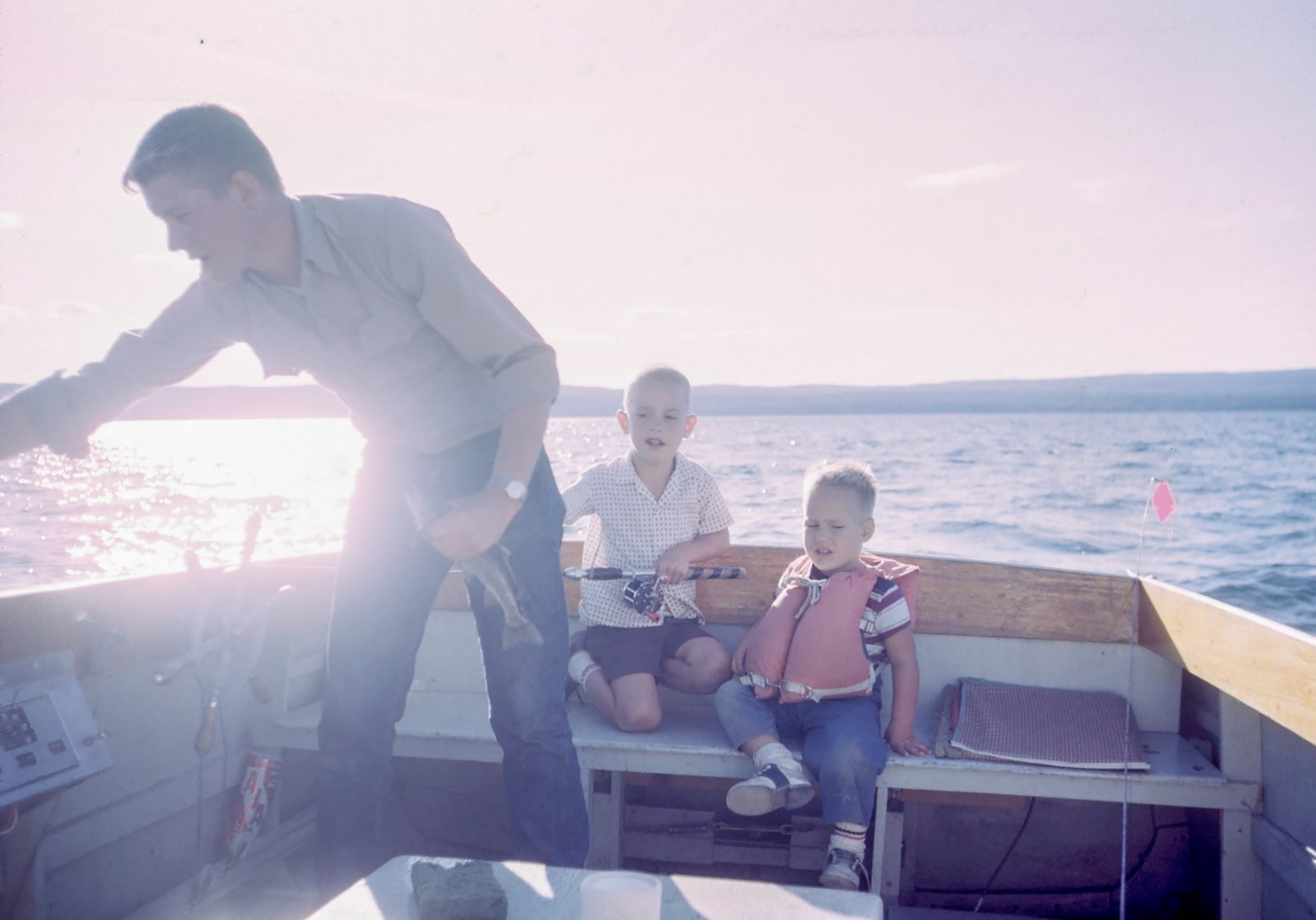 Father and children fishing on a boat.