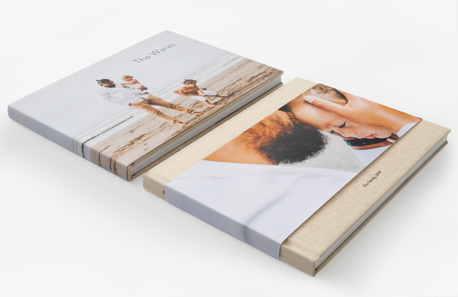 Two premium photo books laying flat, featuring a full jacket and a 3/4 wrap jacket.
