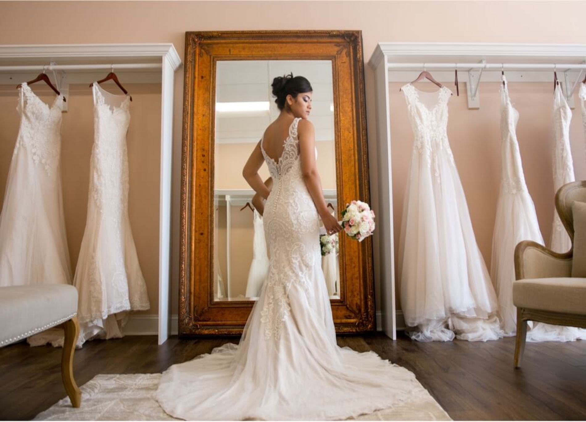 Woman in wedding dress posing in front of mirror of wedding dress shop