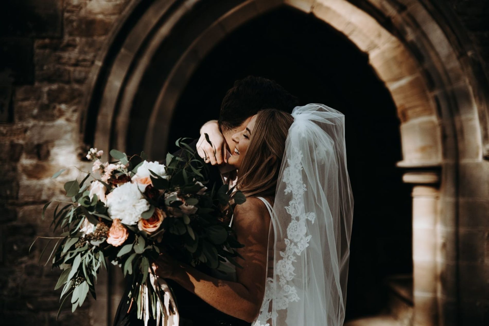 Bride and groom embrace in archway