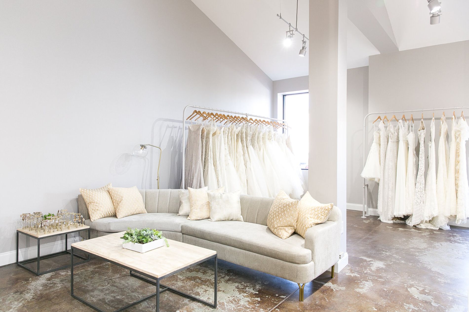 Room with couch and racks of wedding dresses