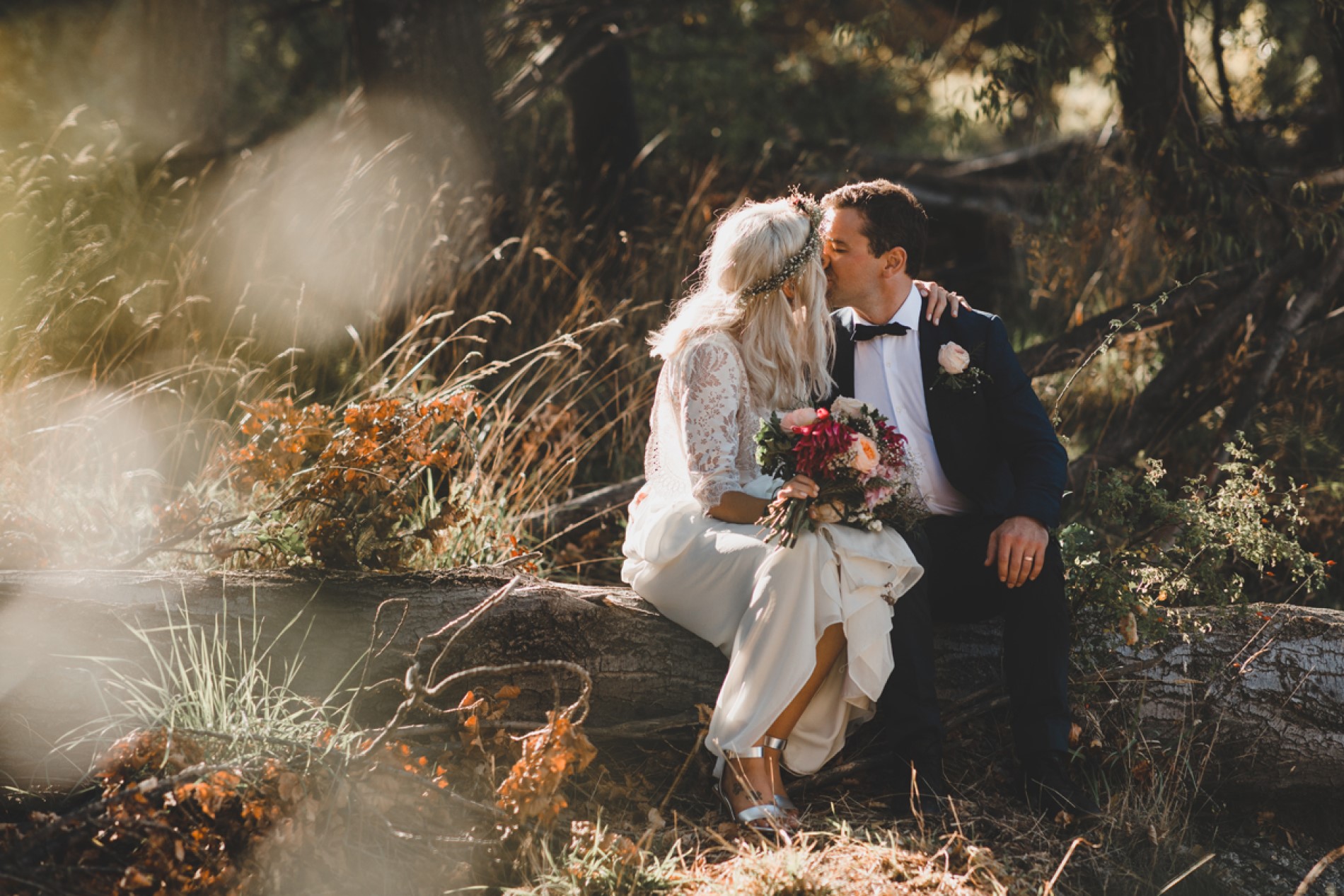 Bride and groom kiss on log