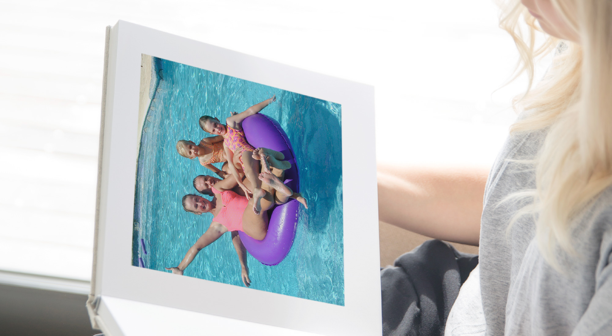 Open photo book with image of a family swimming in a pool.