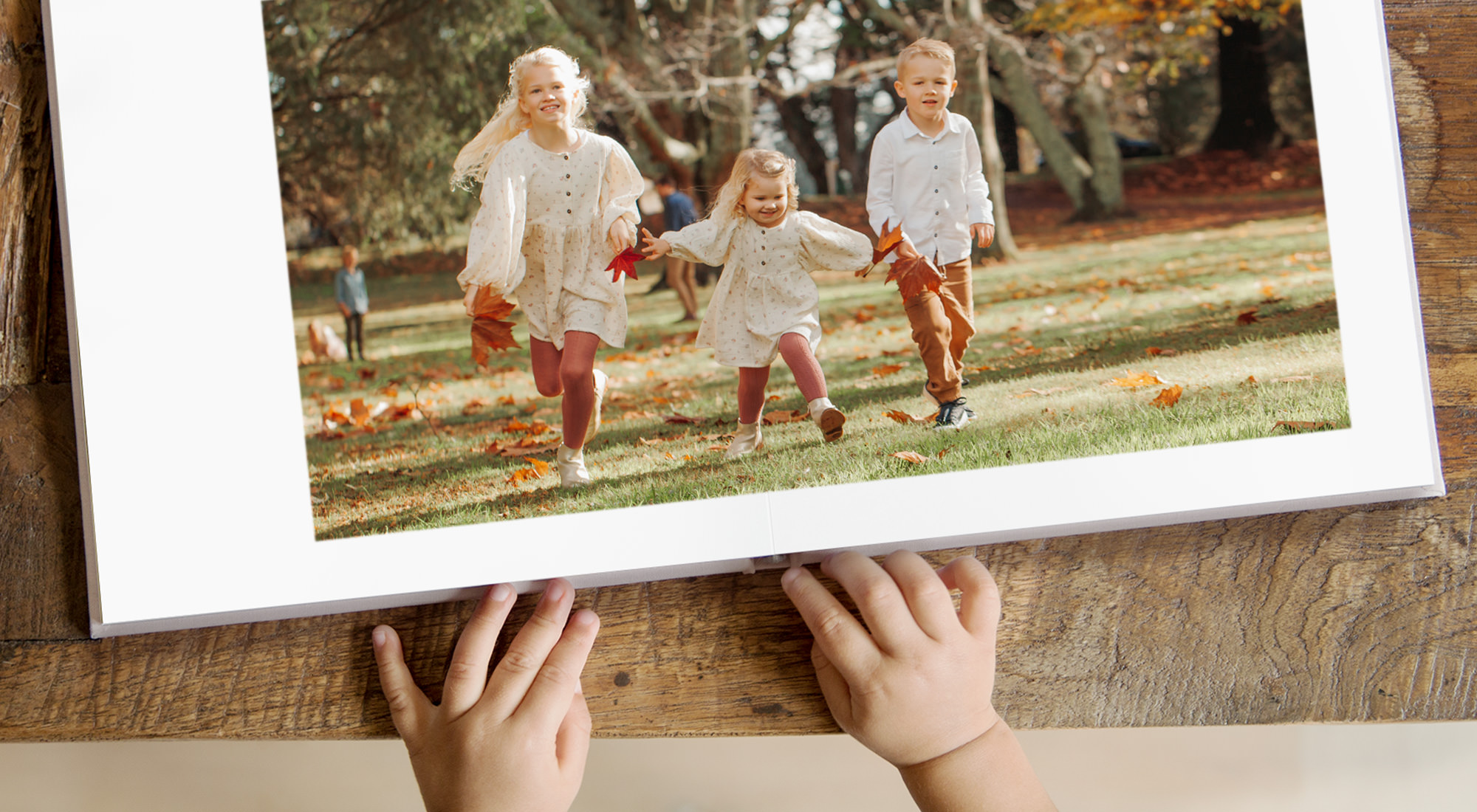 Open photo book with a double page image of three young children at the park.