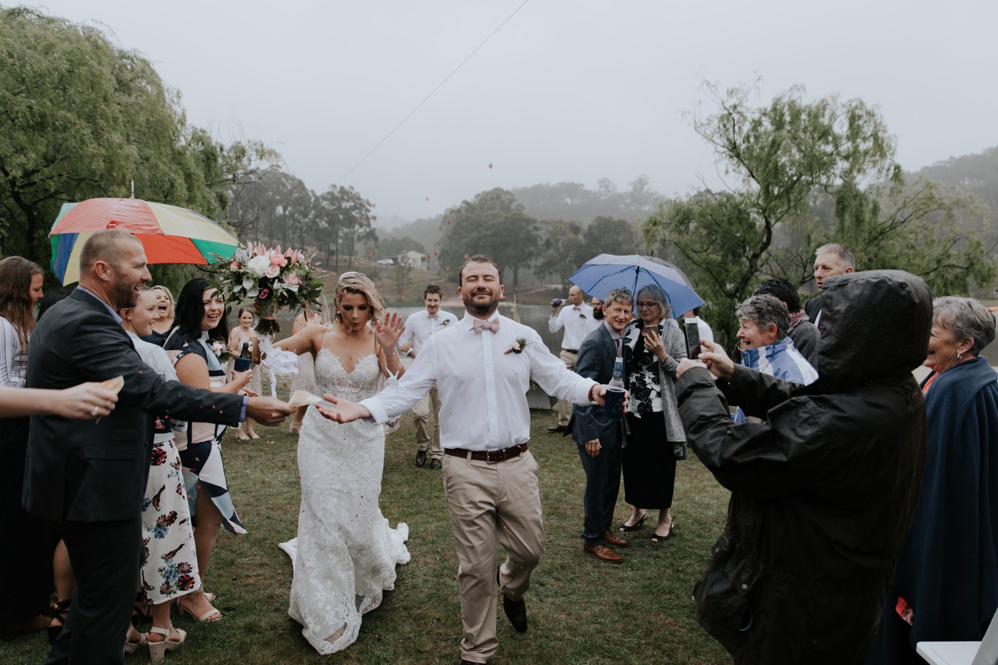 Newlywed couple walking back down aisle in rain.