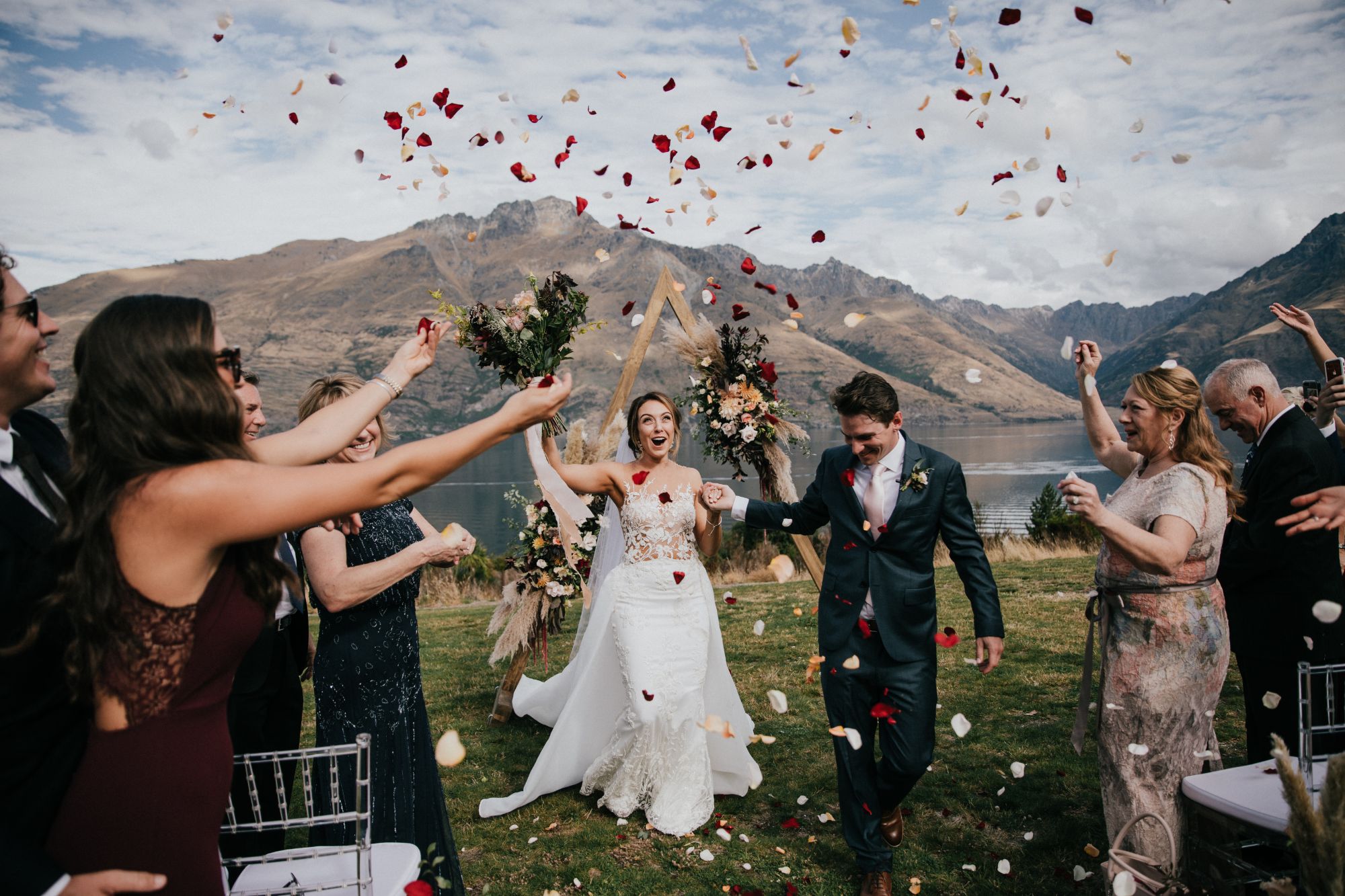 Newlywed couple walking down aisle with flower petals being thrown.