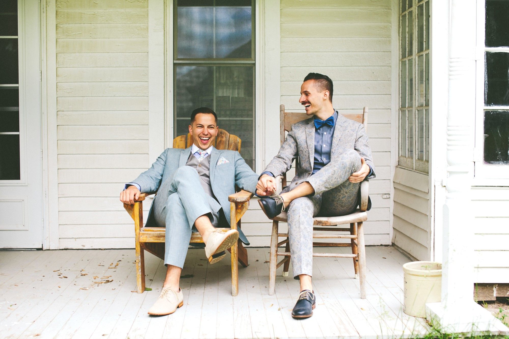 Newlywed grooms sitting on porch.