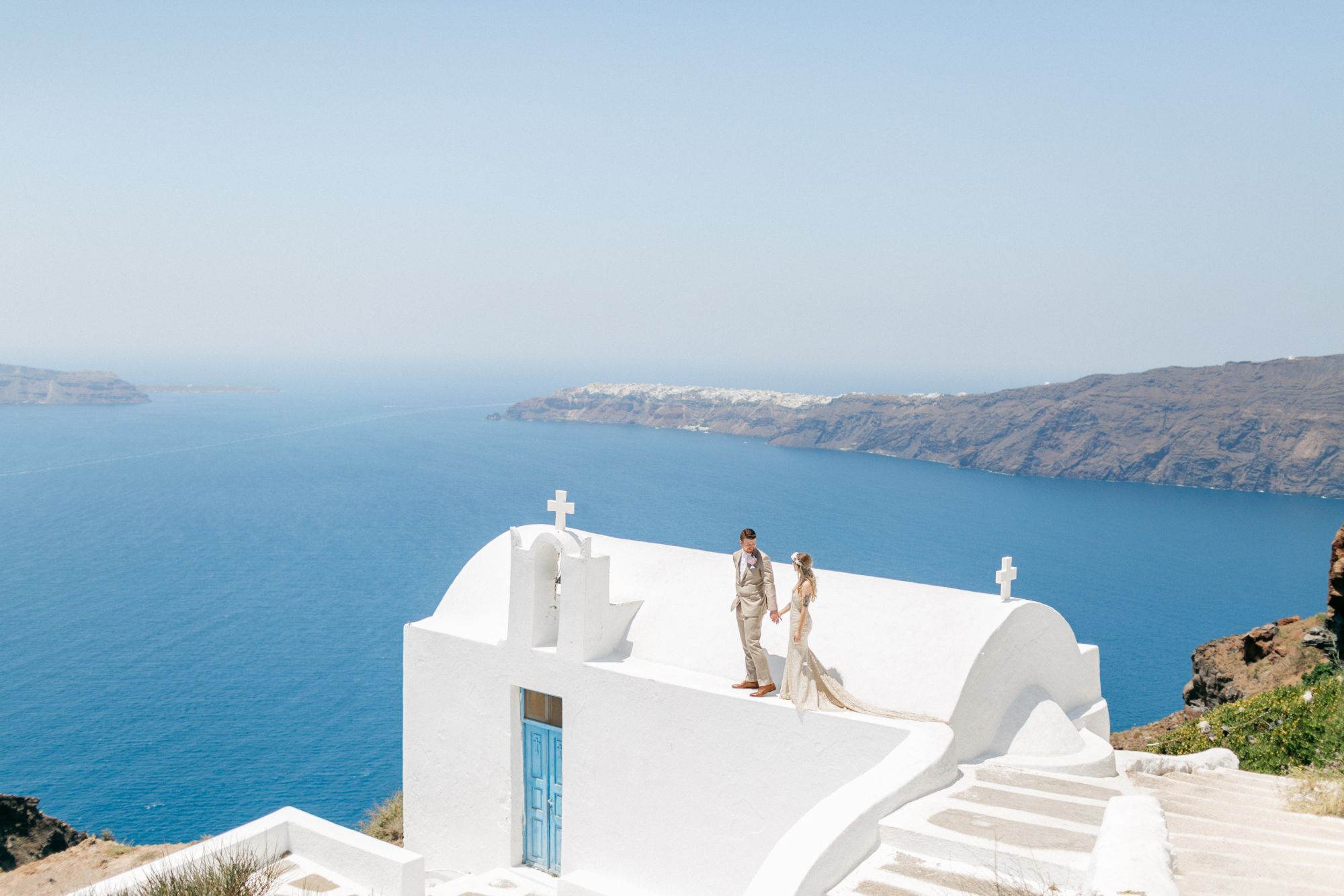 Newlywed couple atop church in Greece.