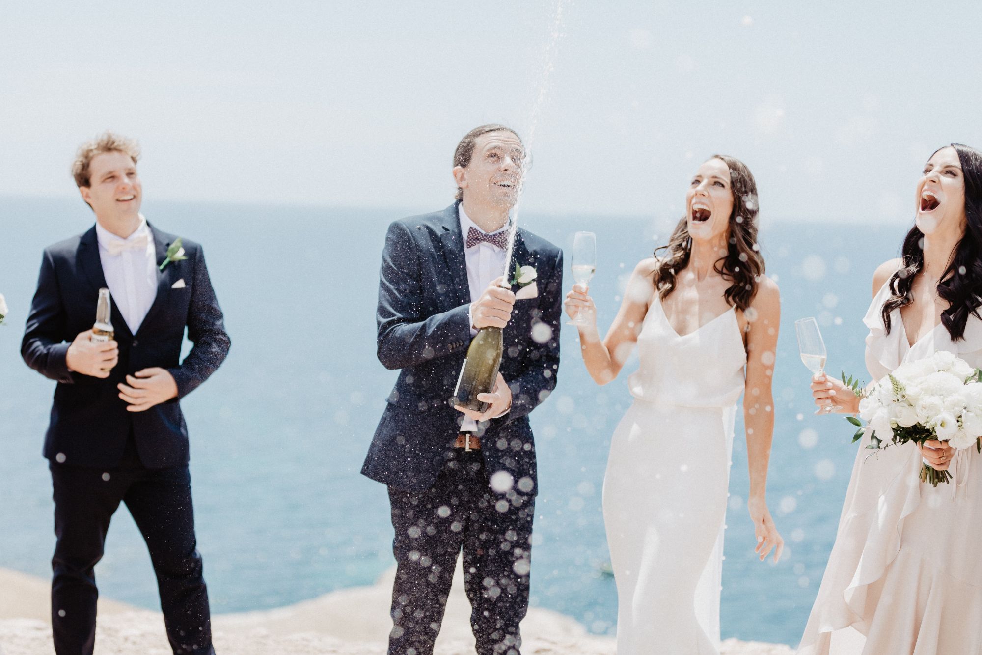Newlywed couple and bridal party spraying champagne.
