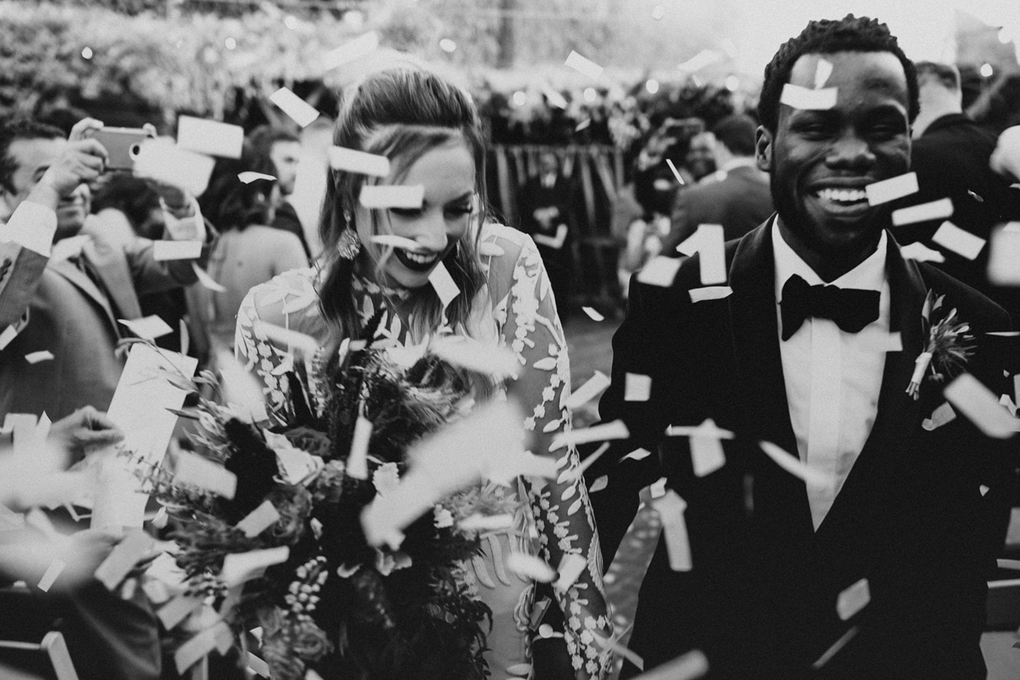 Newlywed couple walking down aisle with confetti being thrown.