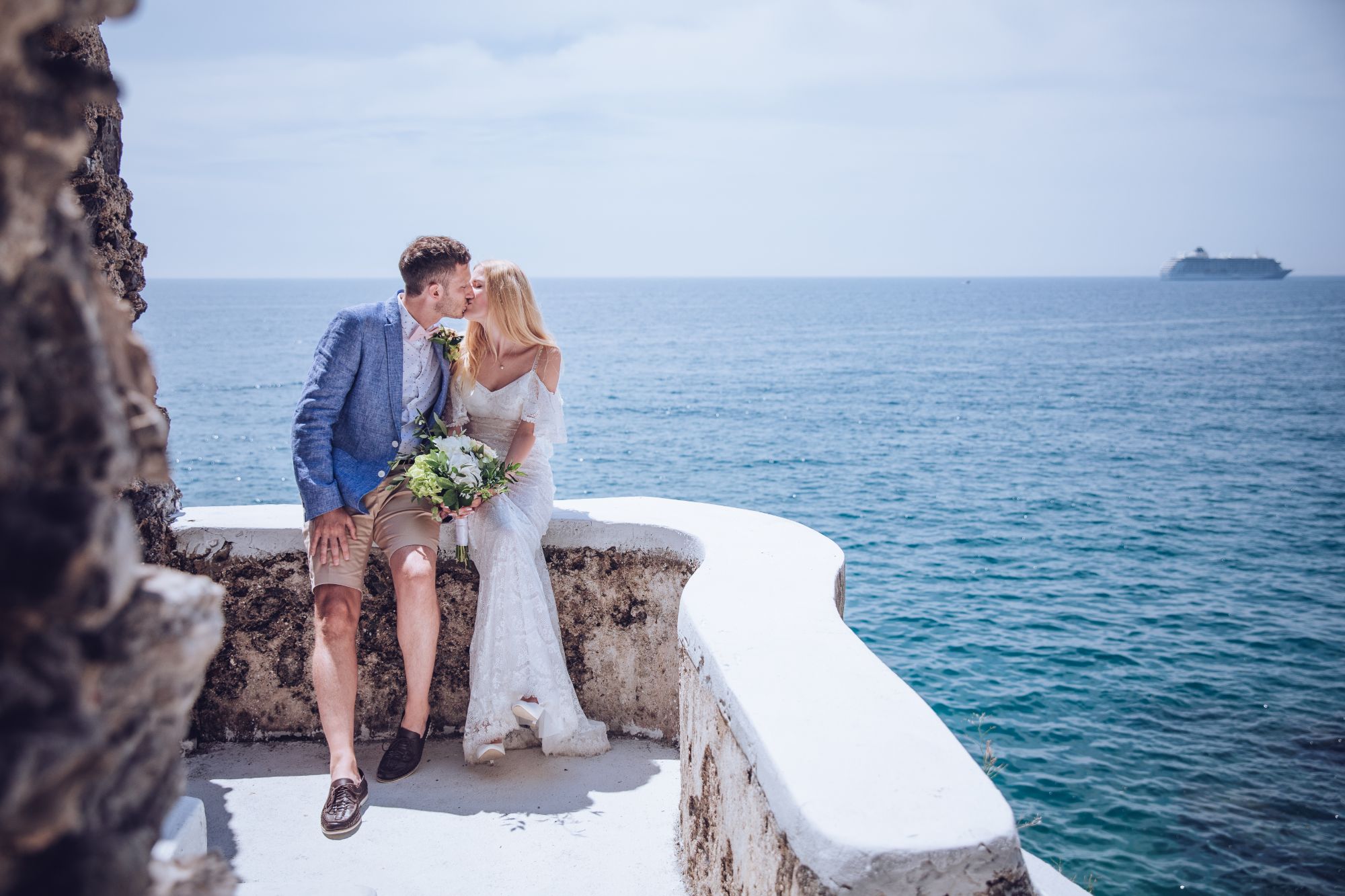 Newlywed couple kissing with sea view.