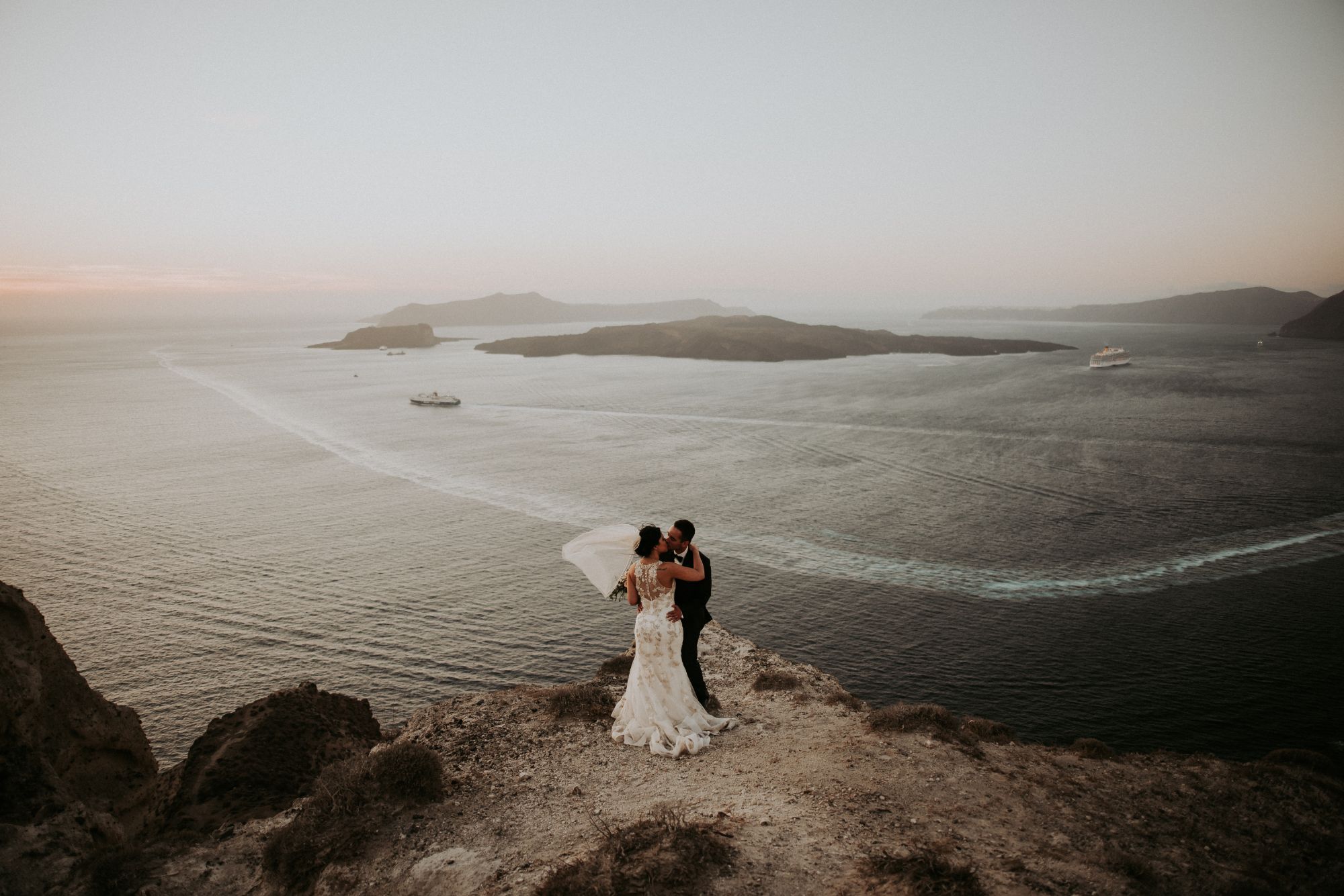 Newlywed couple at cliff's edge overlooking sea.
