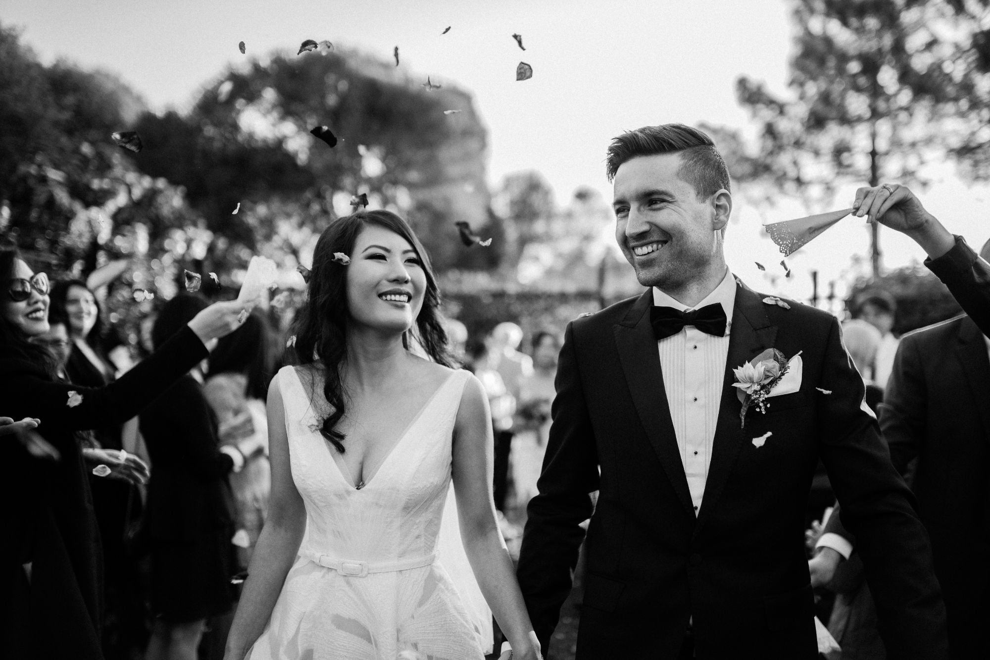 Newlywed couple walking down aisle with flower petals being thrown.