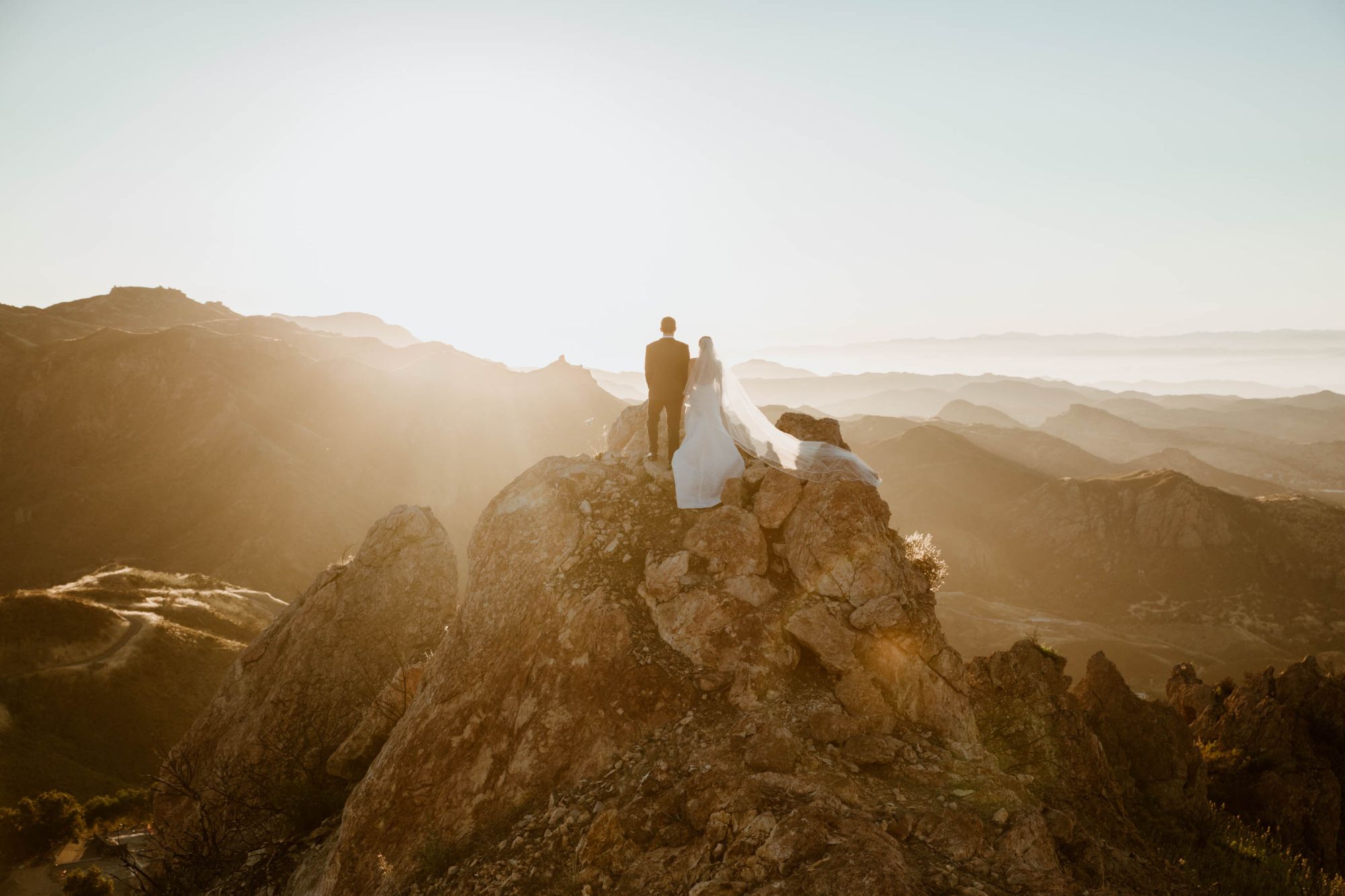 Newlywed couple on clifftop.