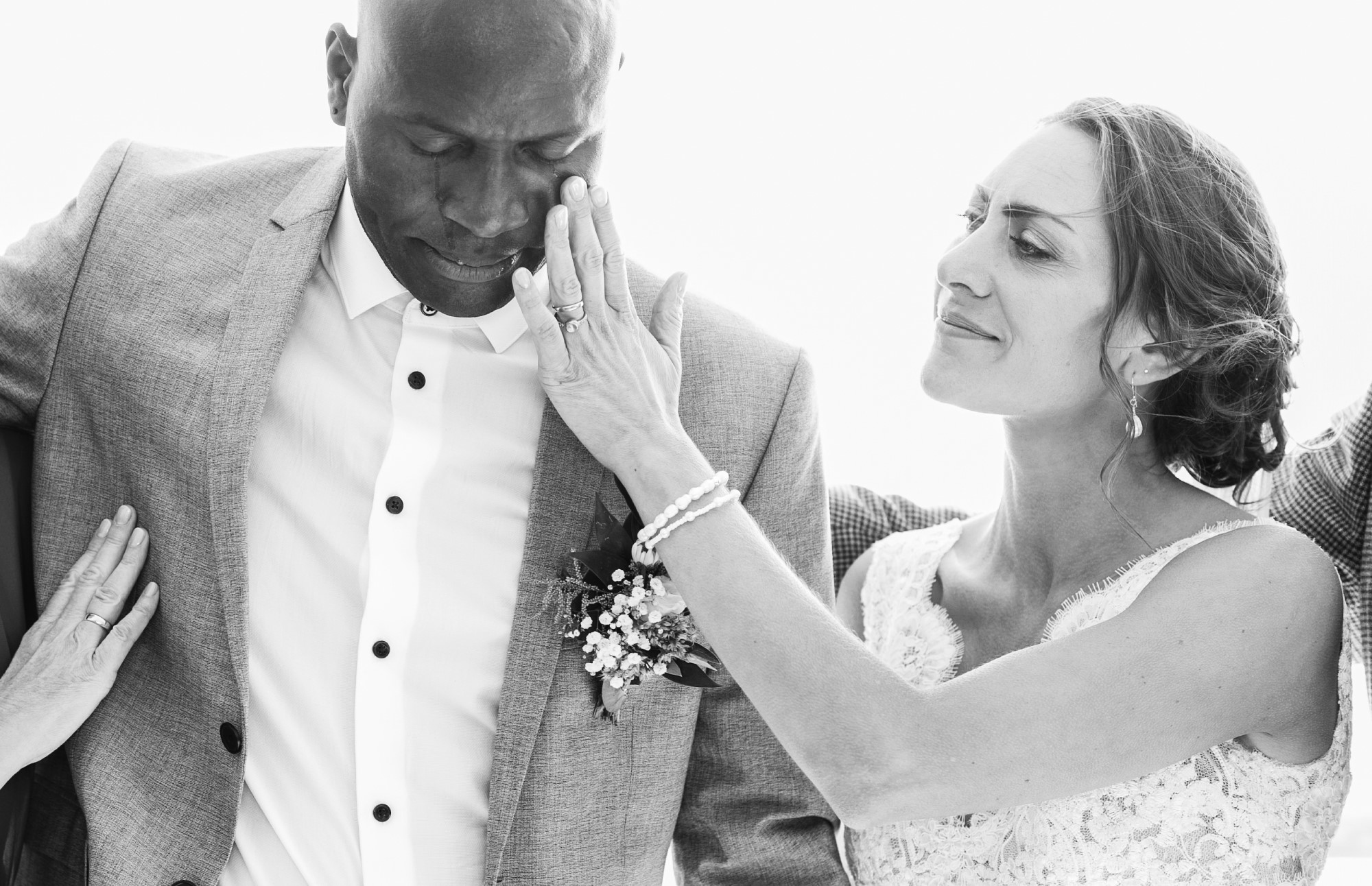 Bride wiping tear from groom's face.