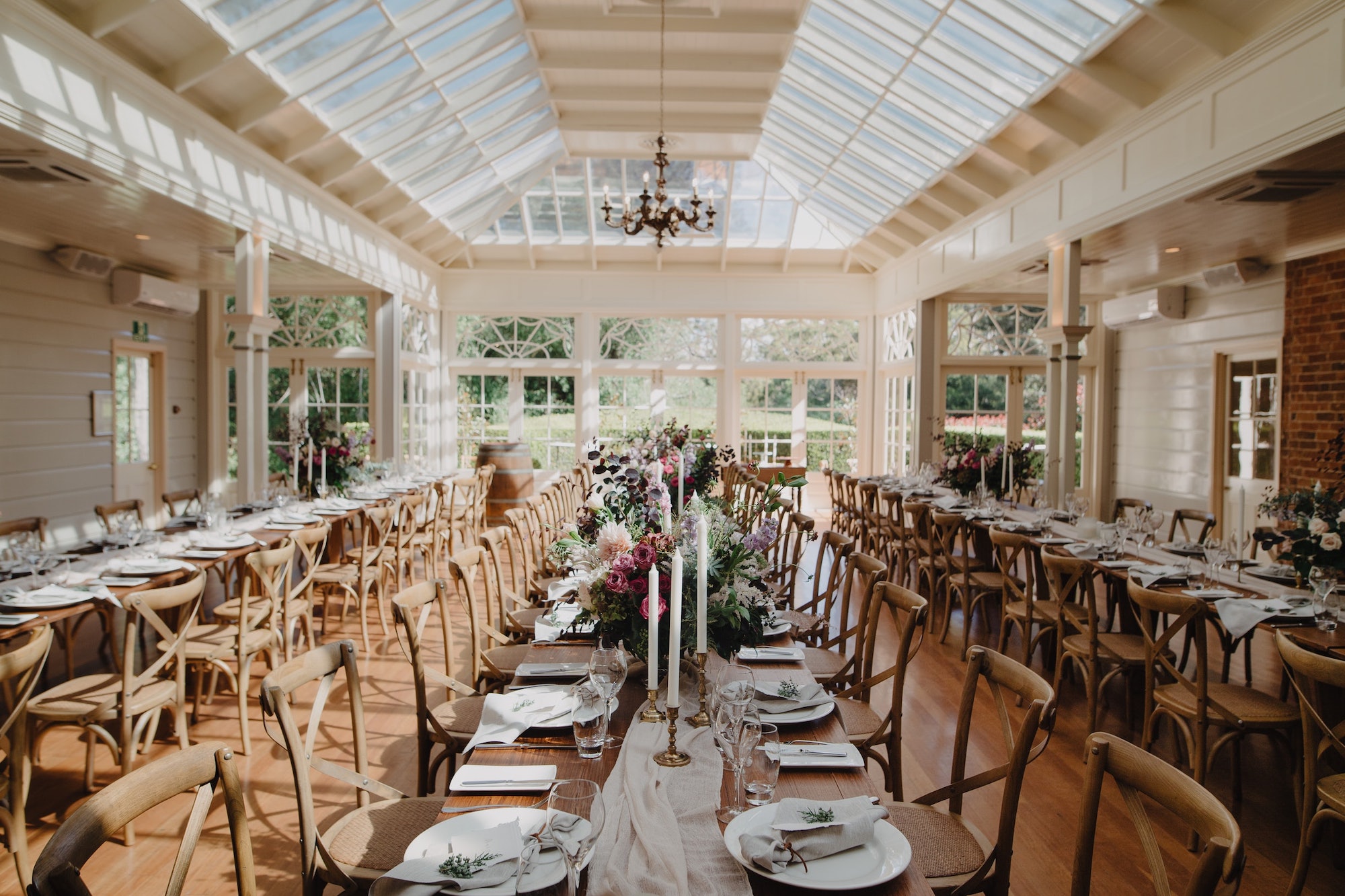 A wedding reception with wooden floors, chairs and tables, flowers and candles