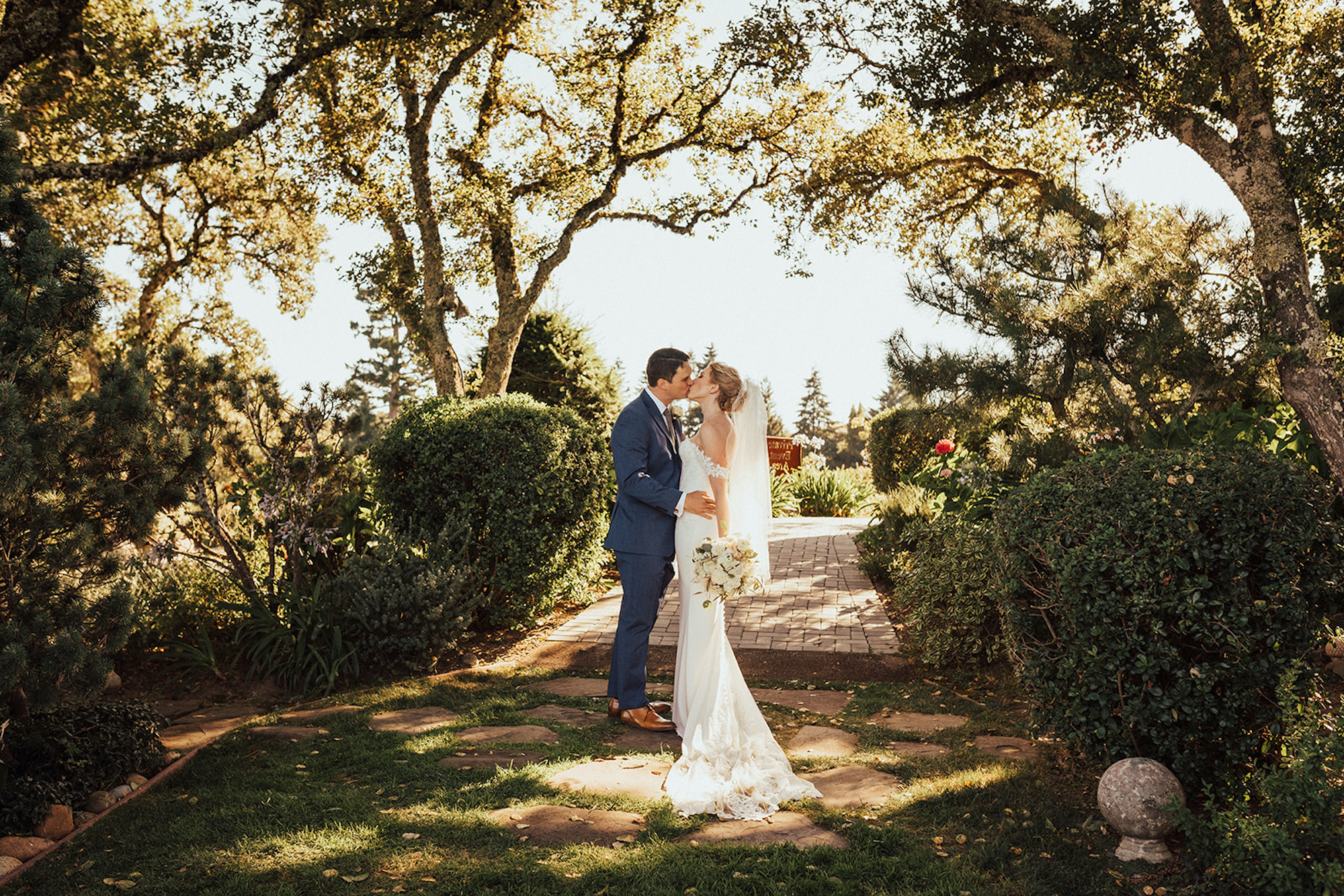 A bride and groom kissing in the garden